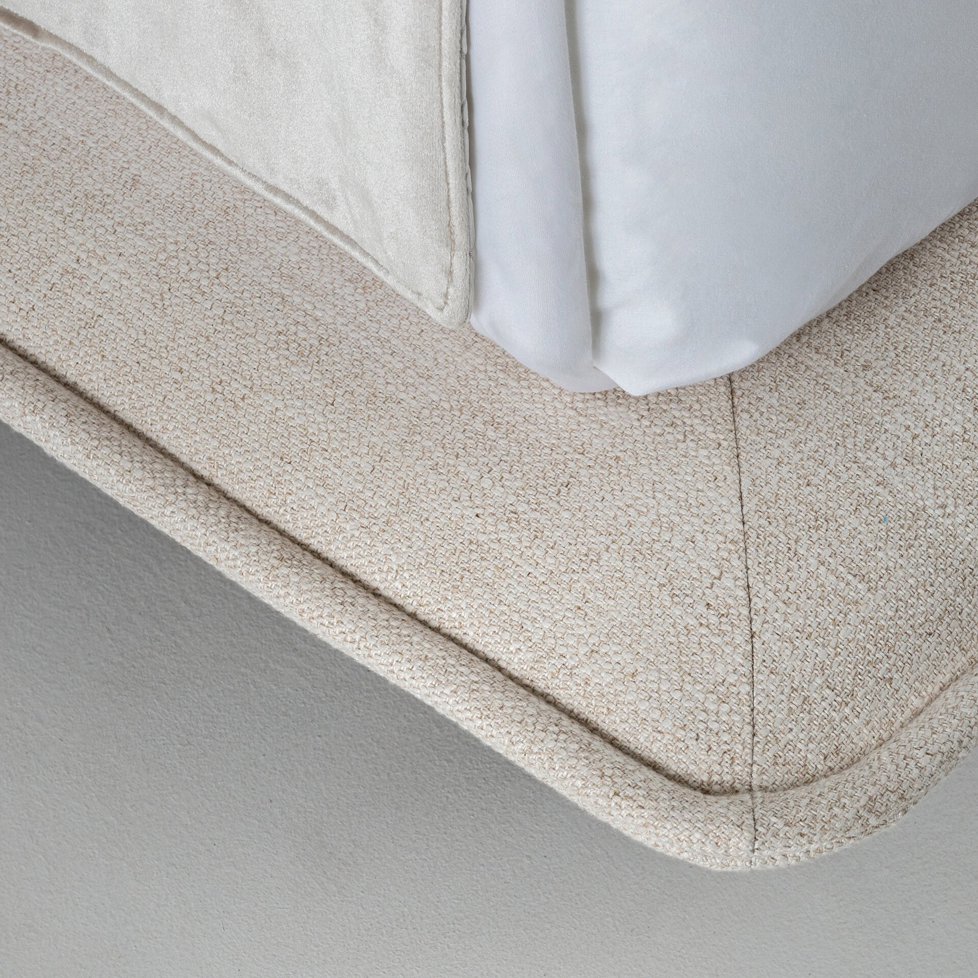 Comfortable beige textured fabric sofa corner with plush white cushions.