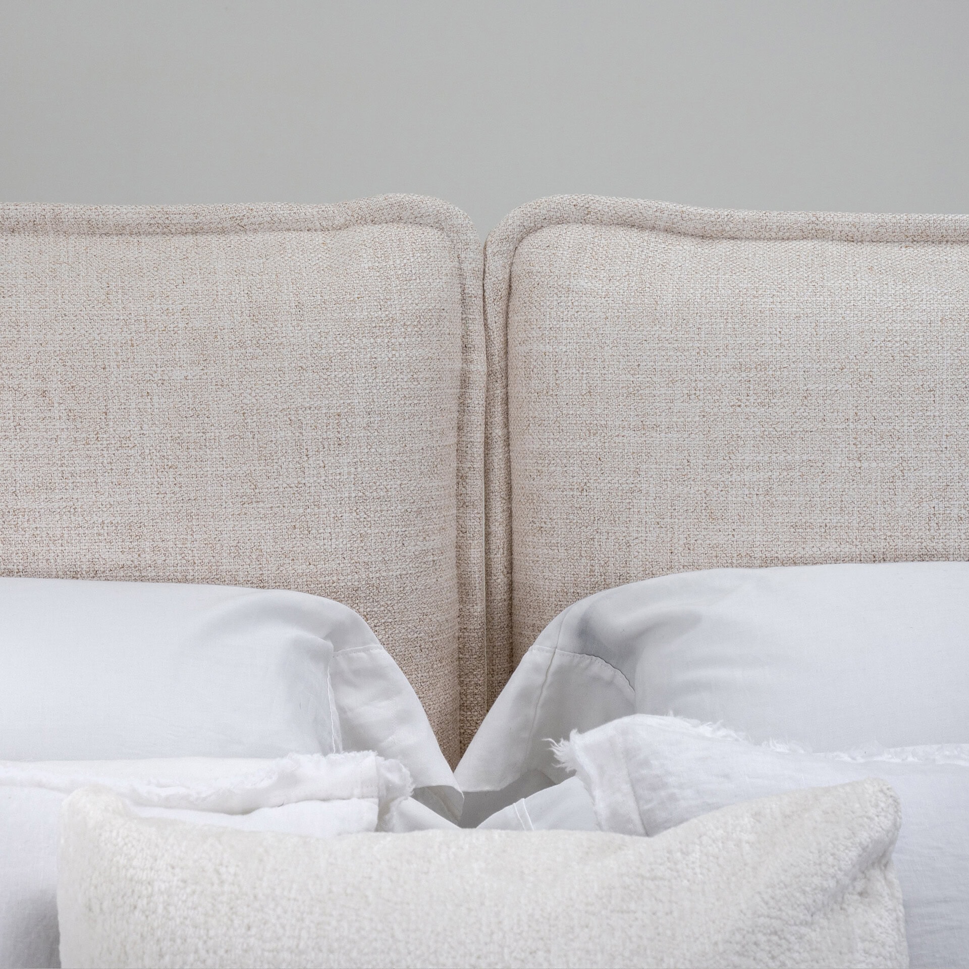 Elegant beige textured headboard with white bedding.