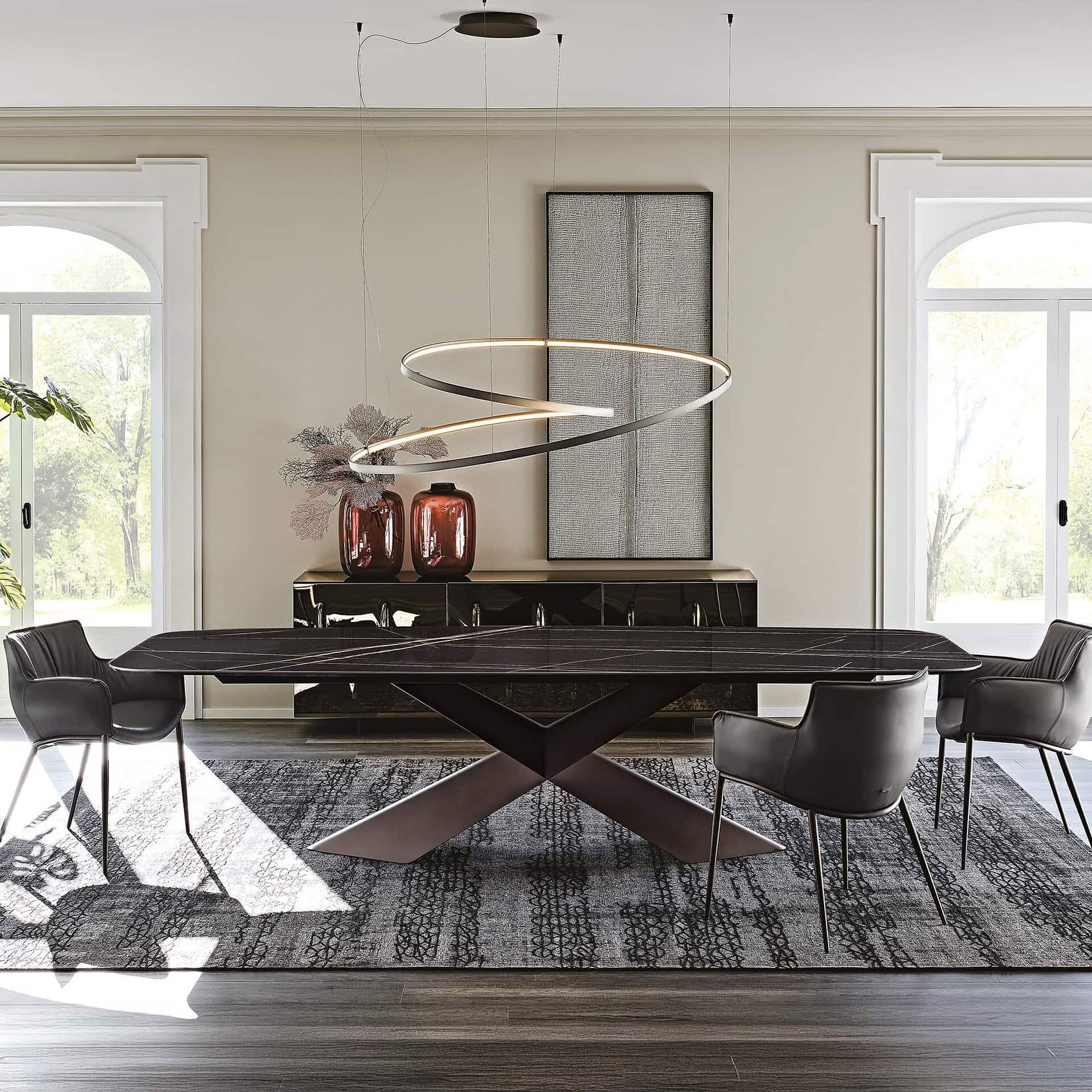 Modern black dining table with sculptural base and contemporary chairs in a stylish dining room setting.