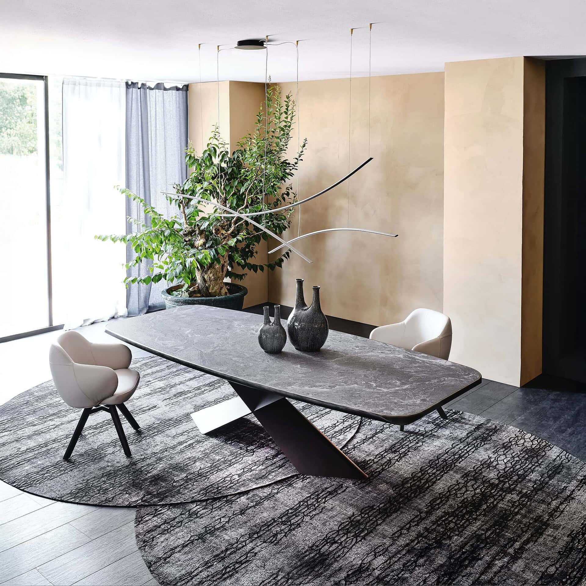 Contemporary dining room with marble table, modern chairs, and artistic decor featuring large potted plant and sleek lighting.
