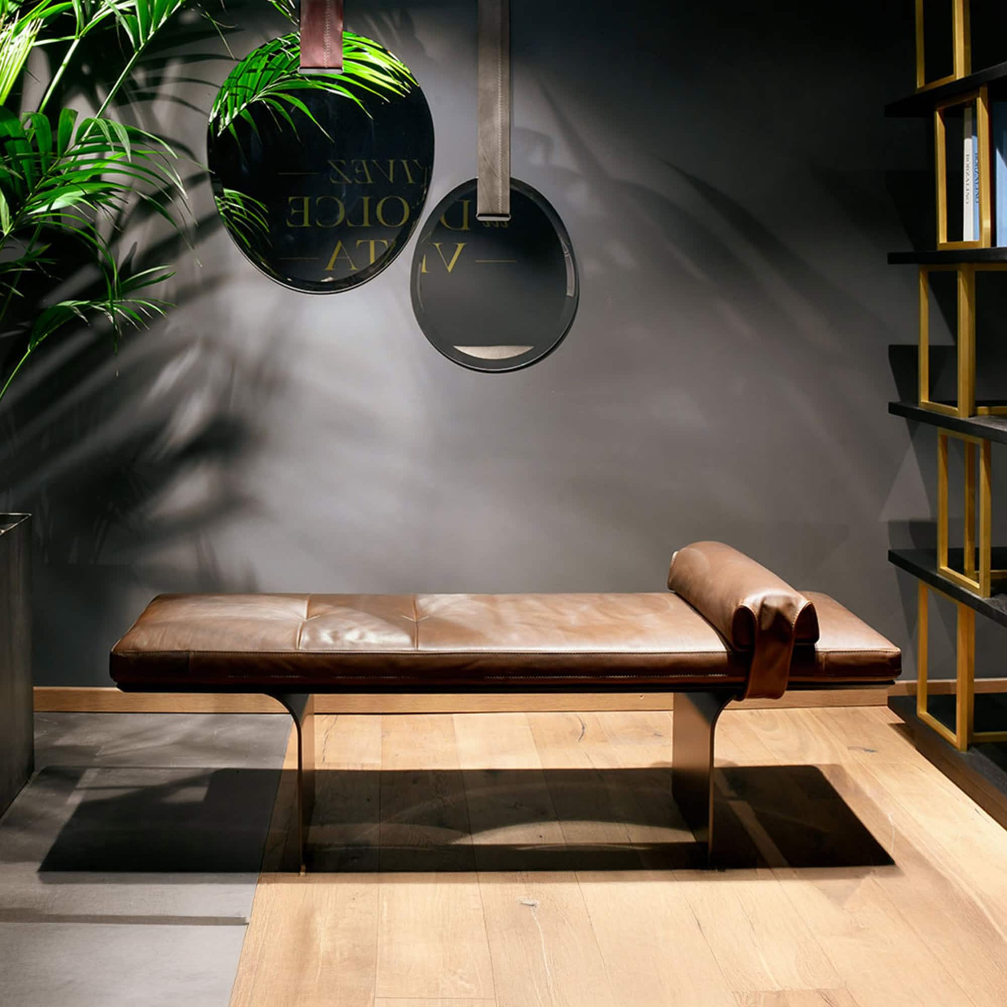 Minerva Floating Upholstered Bench in brown leather with metal base, styled in a modern living space with wood flooring and accent mirrors.