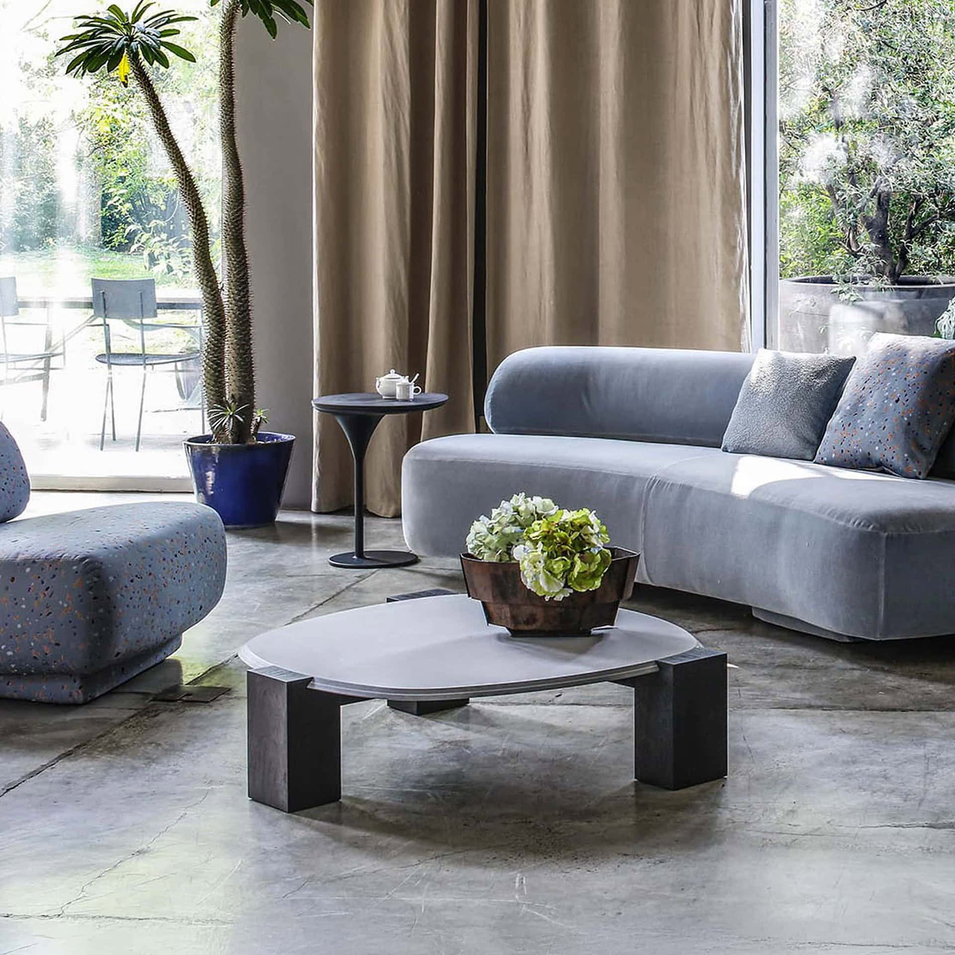 Gogan Sculptural Low Coffee Table with glass top and ash wood base styled in a modern living room with a Gogan Sofa.