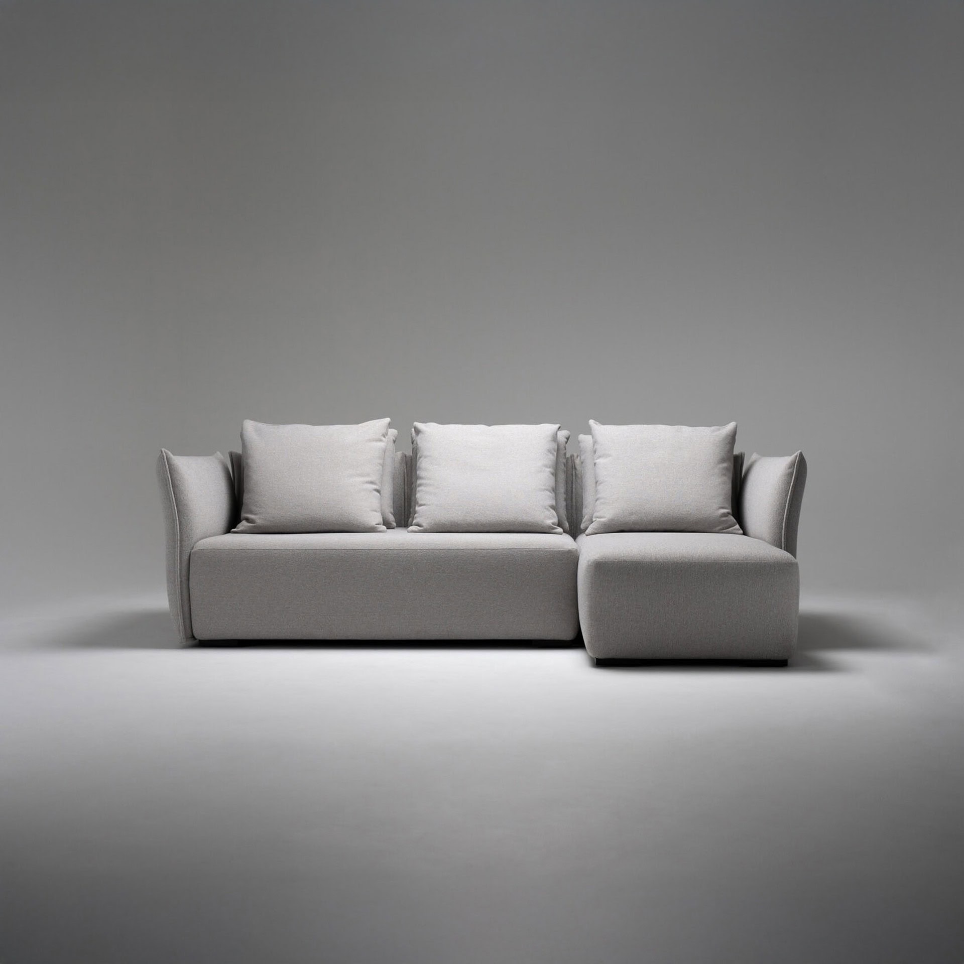 Luxury modern gray sectional sofa with cushions in a minimalistic setting.