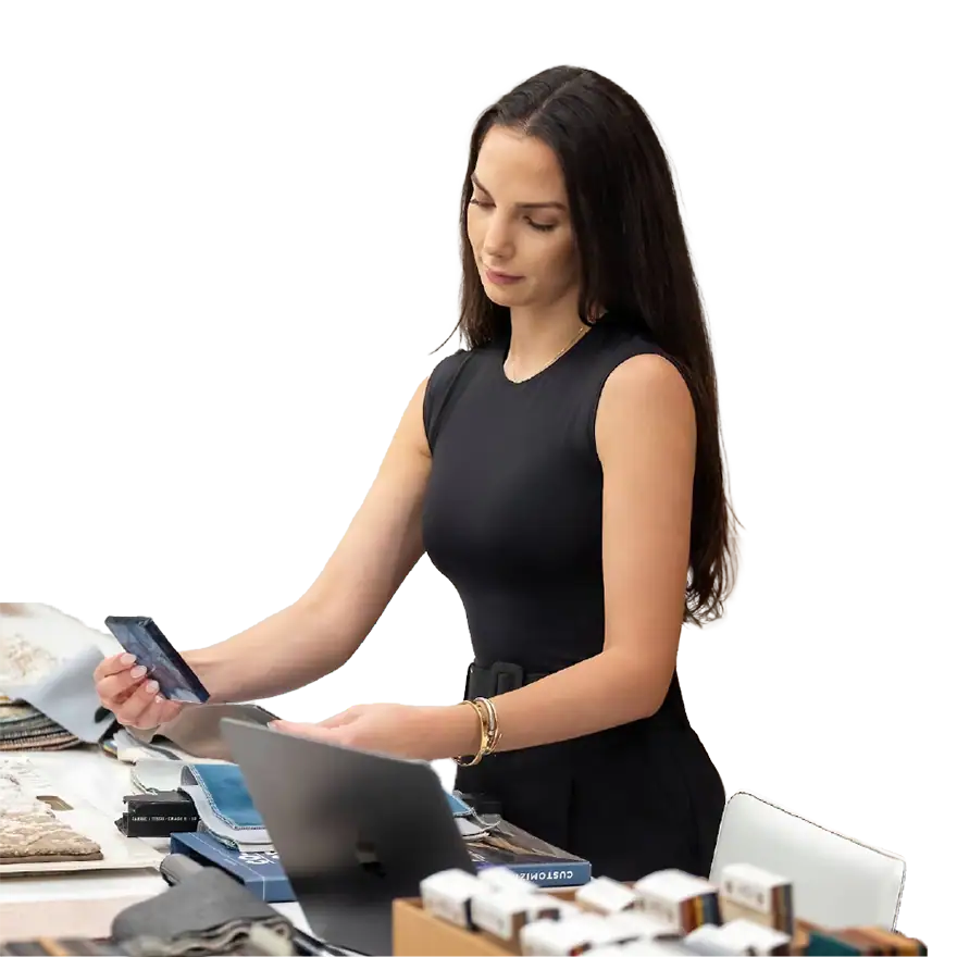 Elegant woman browsing furniture catalog at Sklar Furnishings showroom.