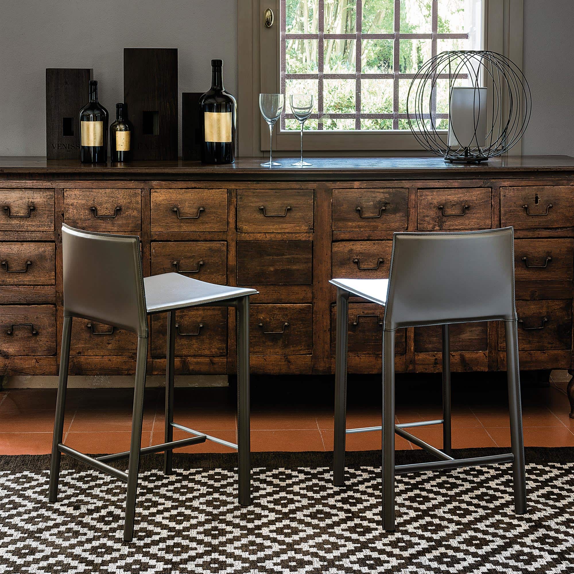 Two Cliff Stools in soft leather with sleek metal legs, styled at a modern bar counter.