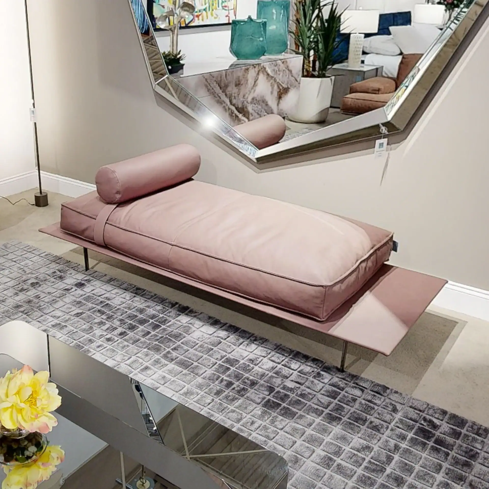 Elegant pink daybed with bolster pillow and sleek metal frame in a contemporary living space.