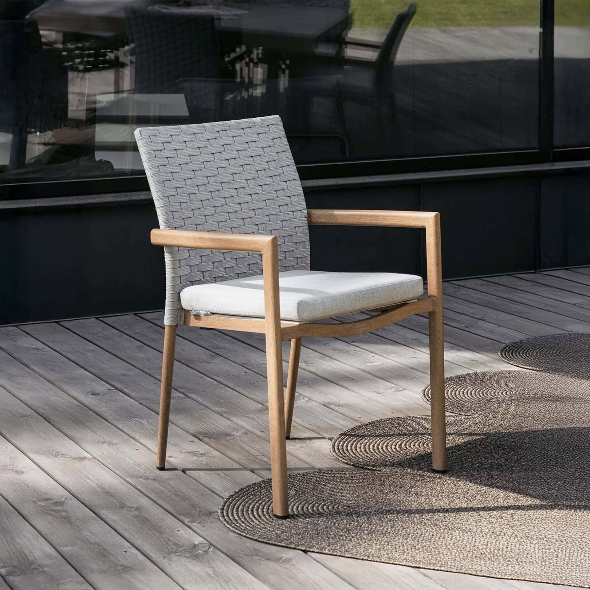 1. Outdoor woven patio chair with wooden armrests on a deck.
