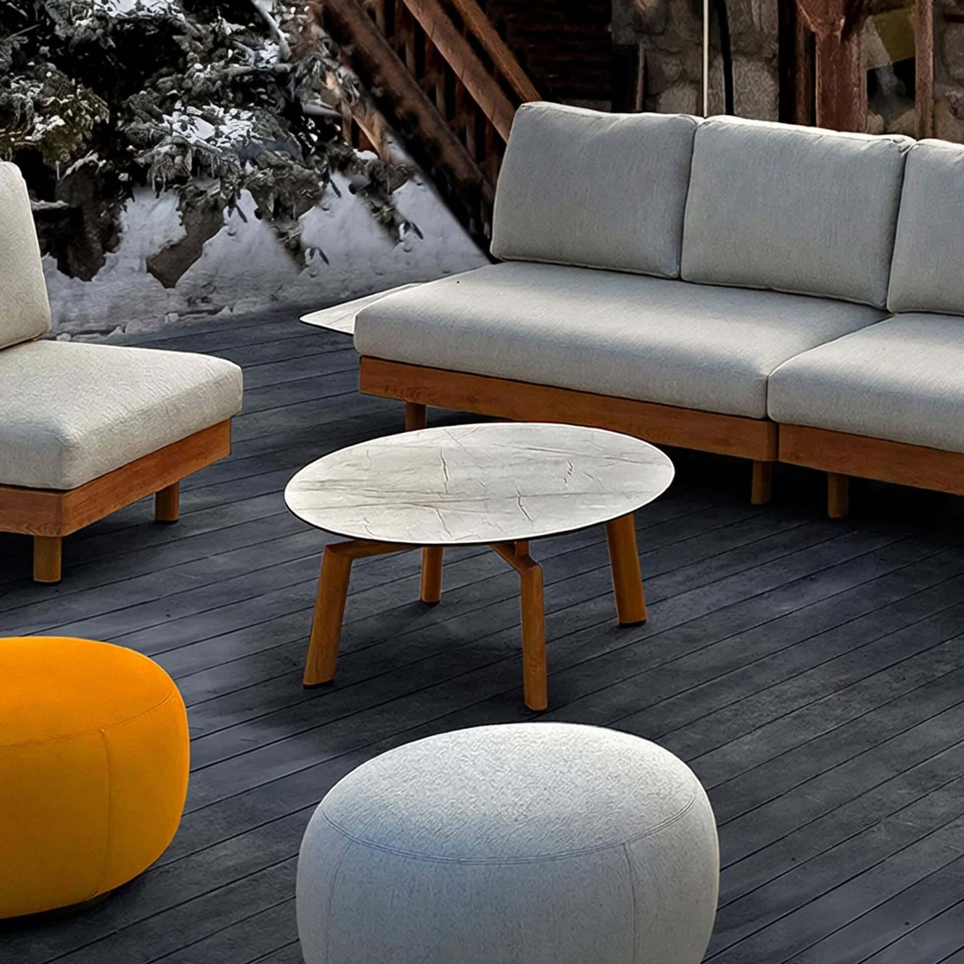 Elegant outdoor living room furniture with modern wooden accents on a dark deck in winter.