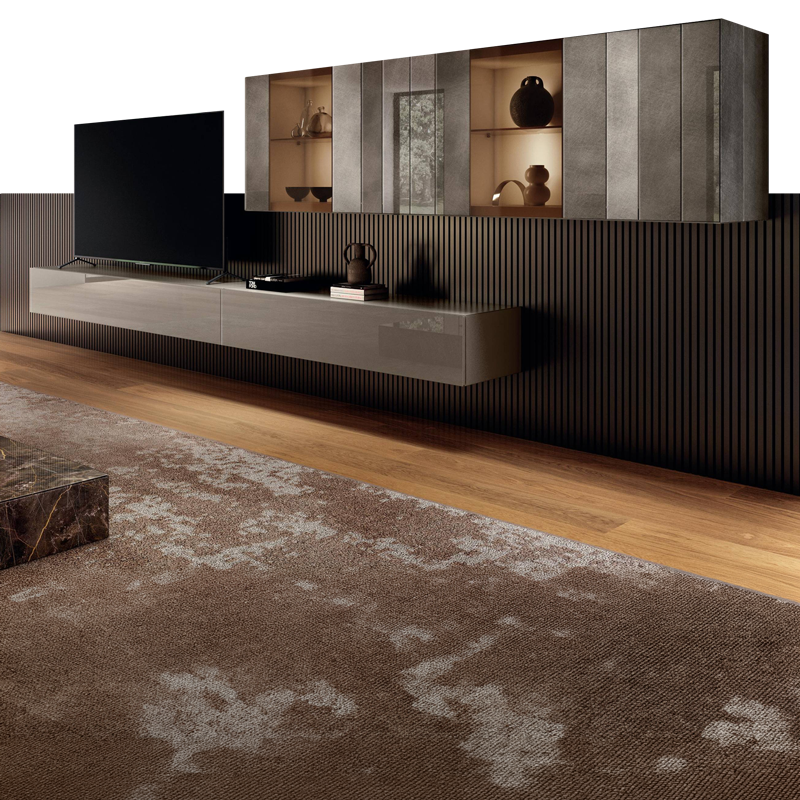 A modern living room with a large black TV on a glossy floating media console. Above it are wall-mounted cabinets, some with illuminated glass fronts, set against dark slatted paneling. A brown patterned rug covers a wooden floor.