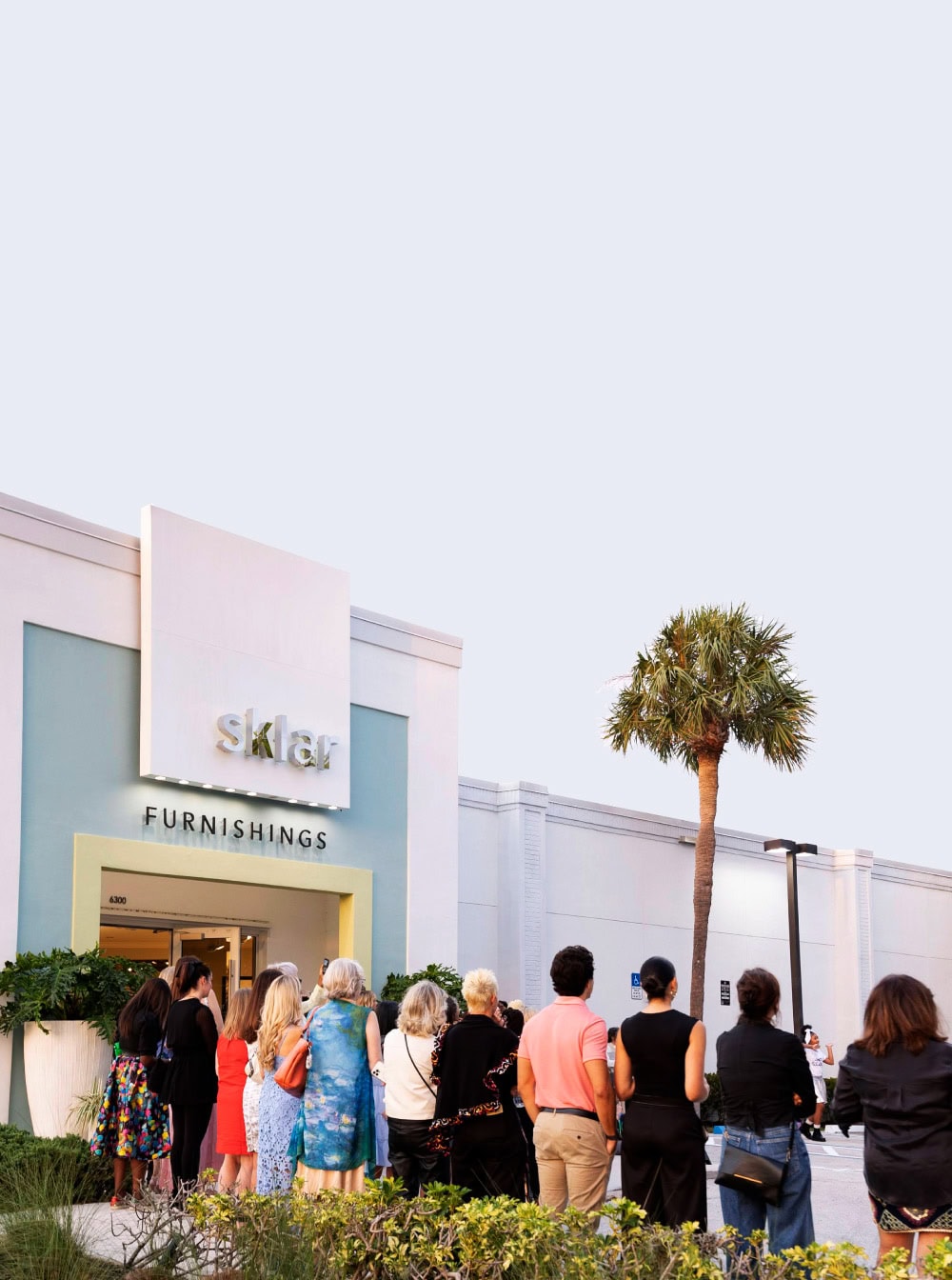 1. Modern furniture showroom exterior at Sklar Furnishings with a line of visitors.