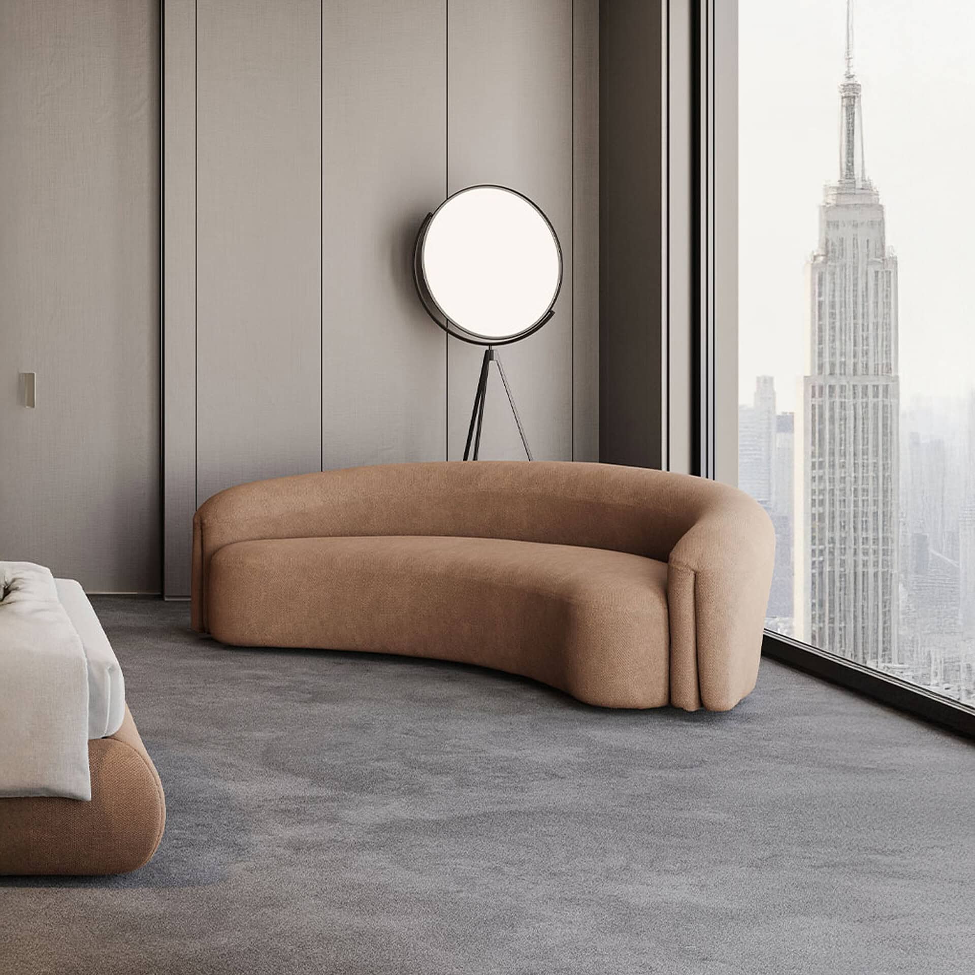 A modern room with a curved brown sofa, a circular floor lamp, and a large window overlooking the Empire State Building and a city skyline.