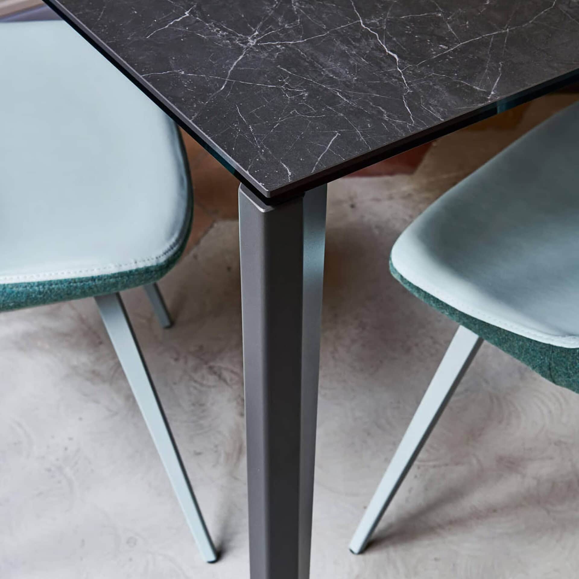 Close-up of the Diamond Extendable Dining Table corner showing textured top and sleek metal legs.