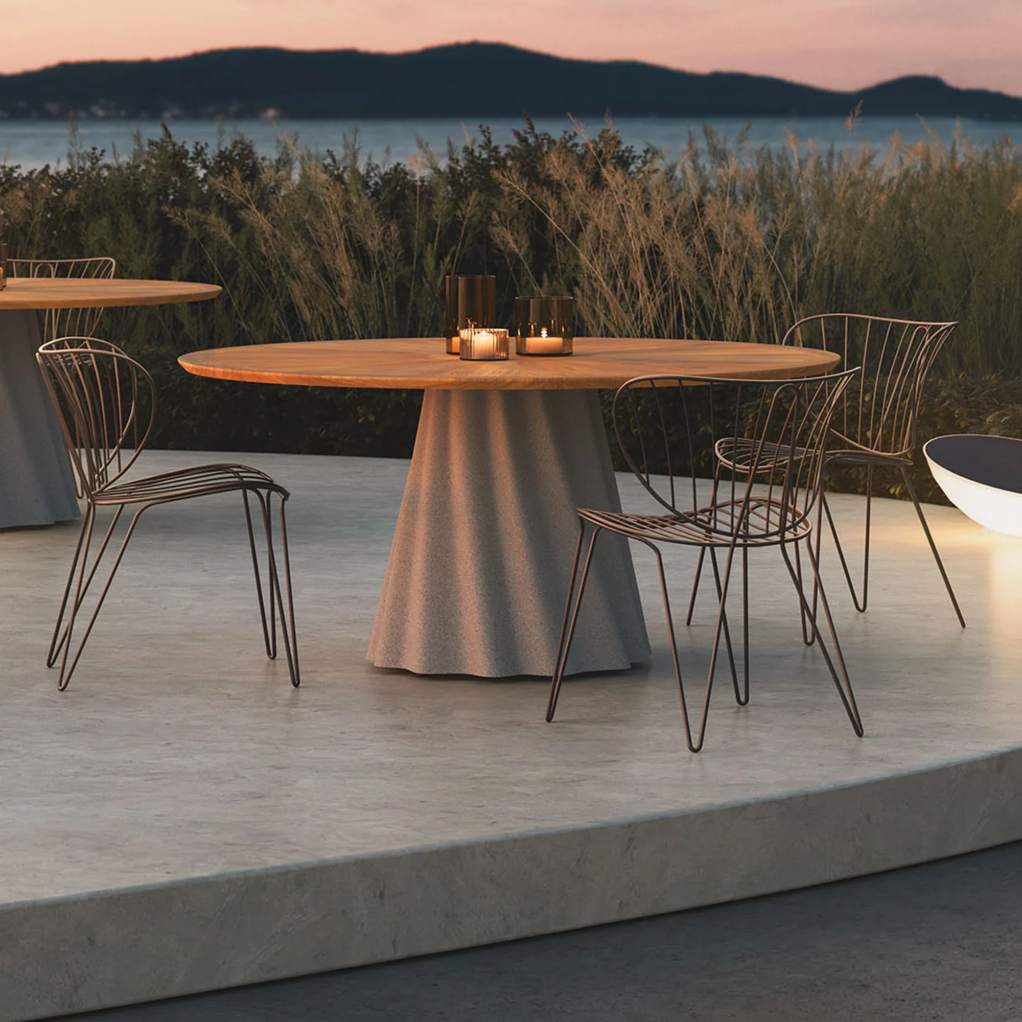 Onda Round Outdoor Dining Table with Iroko wood top and concrete base, positioned by an ocean view pool.
