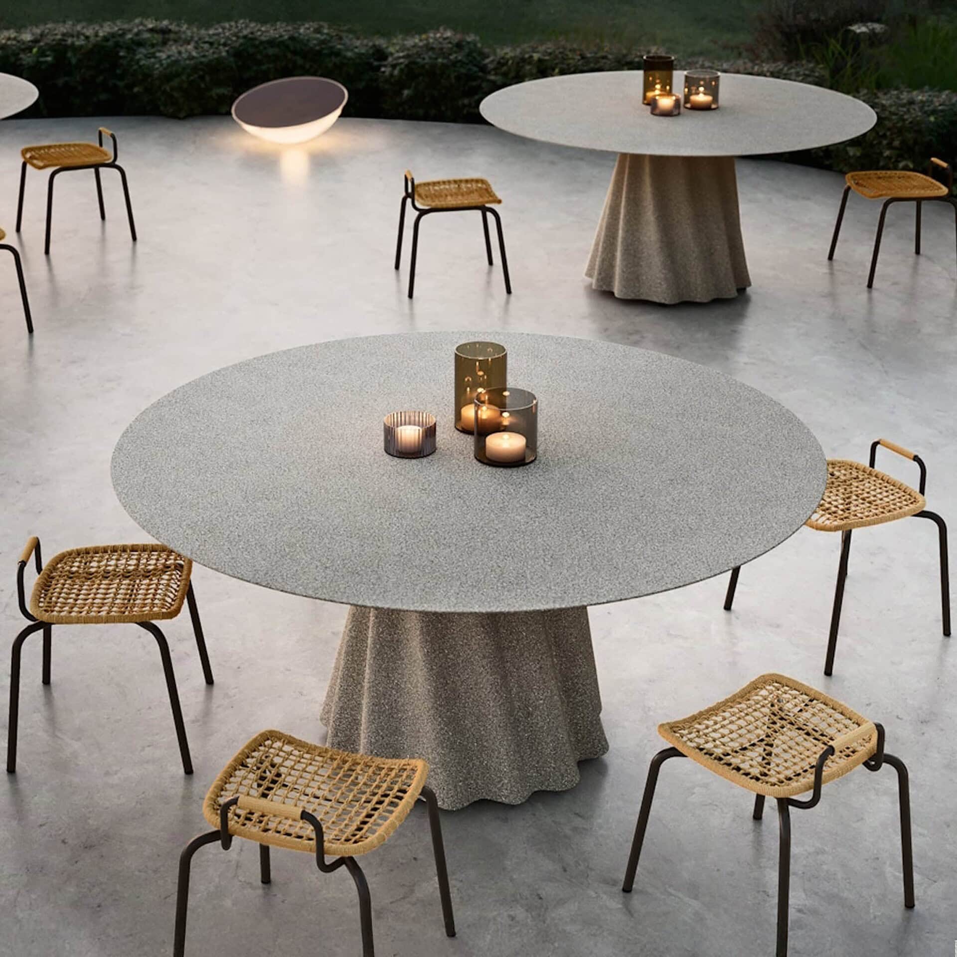 Multiple Onda Round Outdoor Dining Tables with concrete tops arranged in an outdoor dining setting.