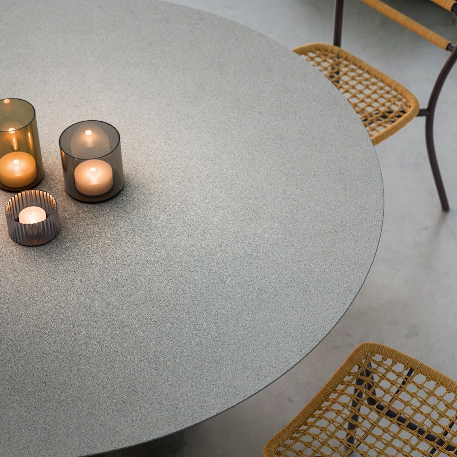 Close-up of the Onda Round Outdoor Dining Table in concrete top finish with decorative candles.