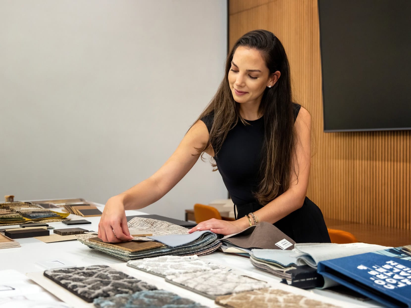 Elegant woman analyzing fabric and material samples for custom furniture at Sklar Furnishings showroom.