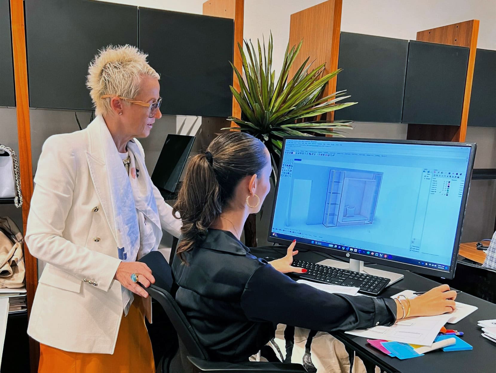 Contemporary office design with digital 3D furniture modeling on a large screen.