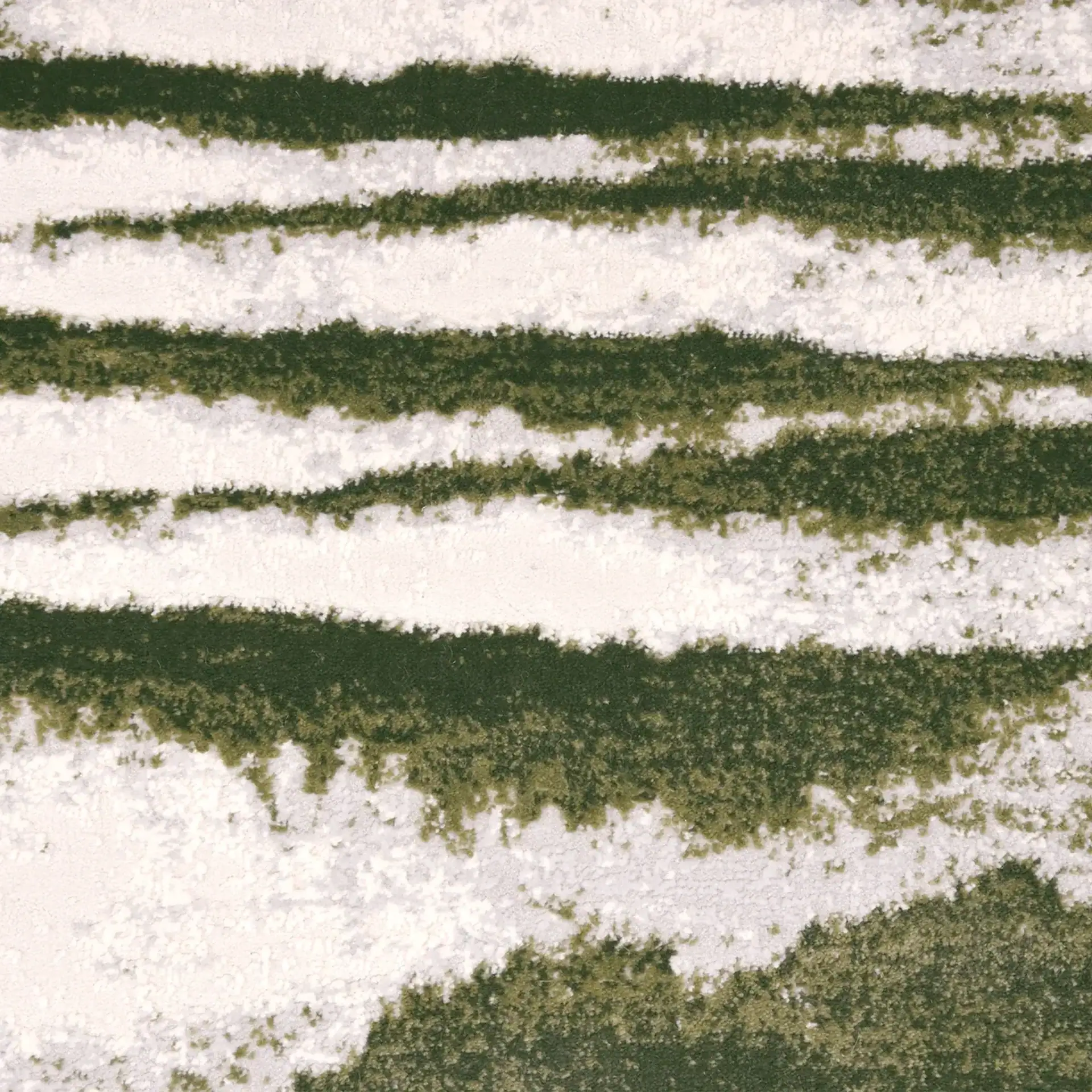 Aerial view of snow-covered fields with green patches and furrows.