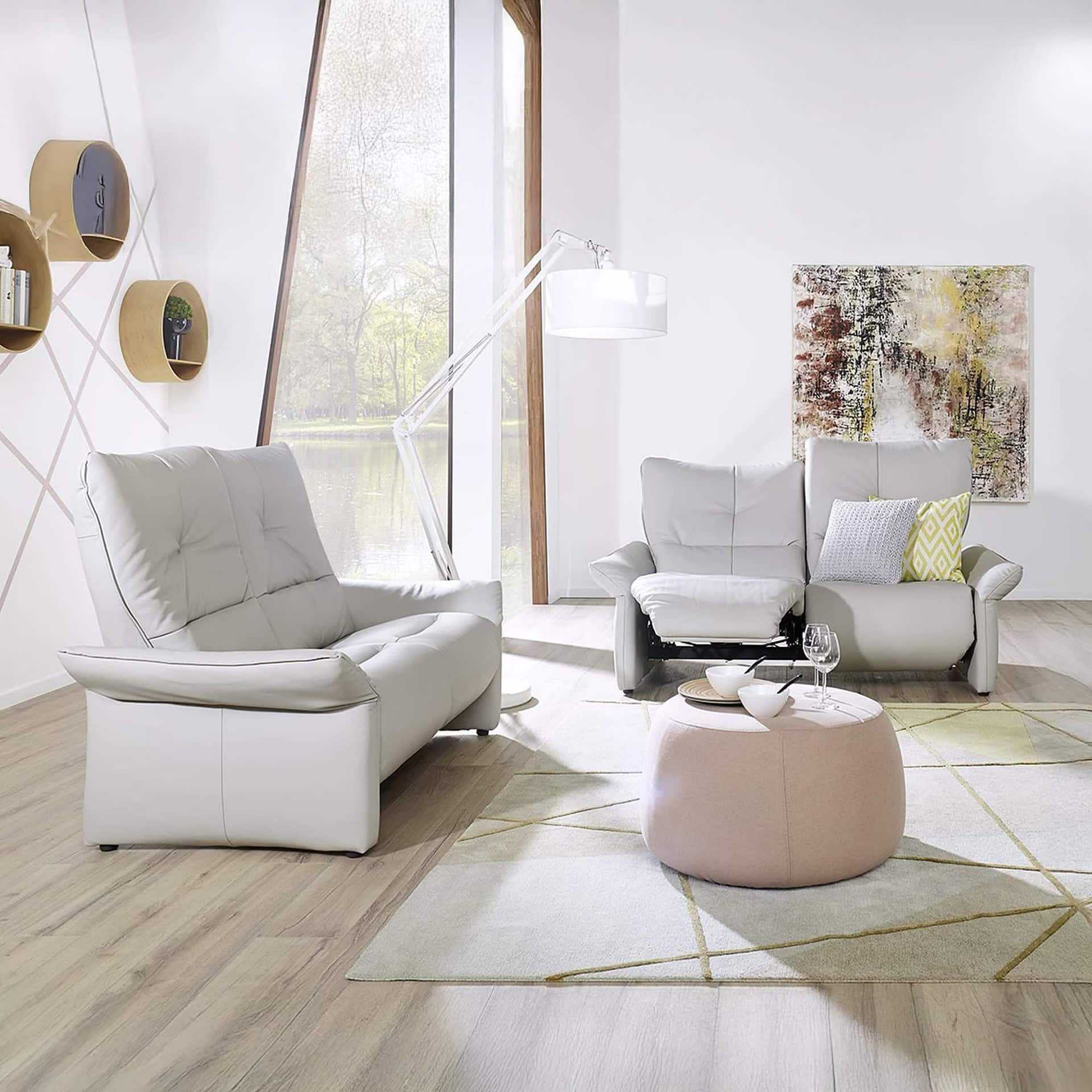 Modern white leather sofas in a stylish living room with large window and contemporary decor.
