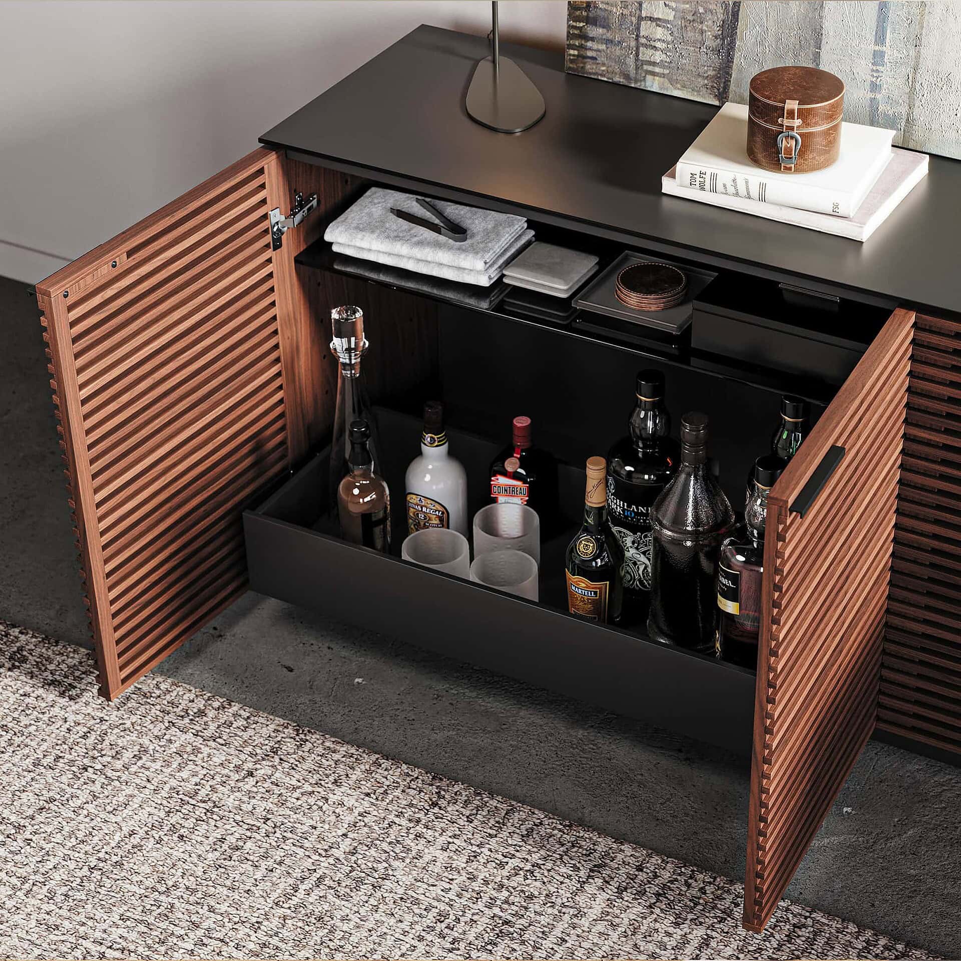 Sleek black and wood bar cabinet with liquor bottles, glassware, and storage compartments.