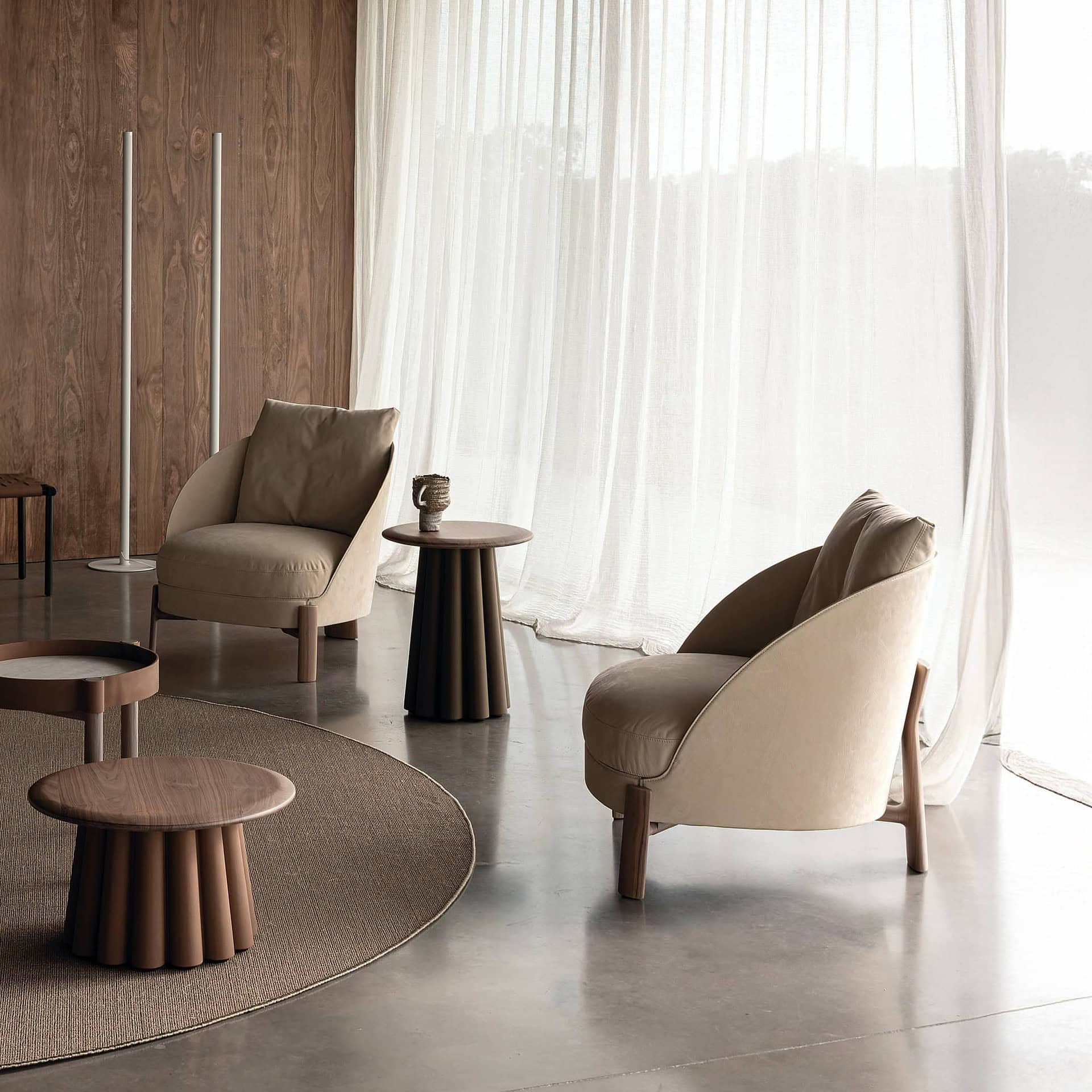 Stylish modern living room with beige armchairs and wood accent wall by Sklar Furnishings.