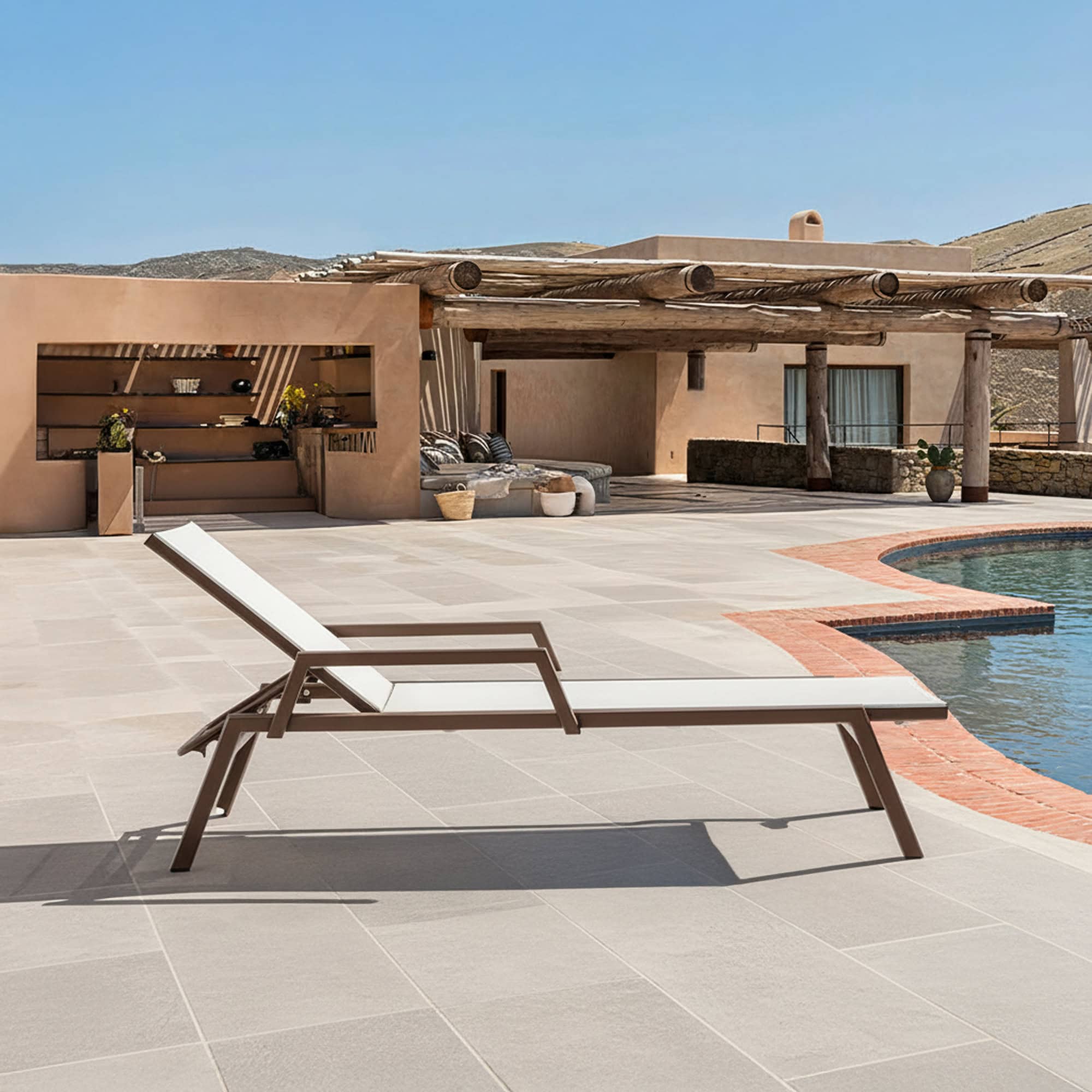 Luxurious outdoor chaise lounge on poolside patio with ocean view, perfect for relaxation and outdoor living.