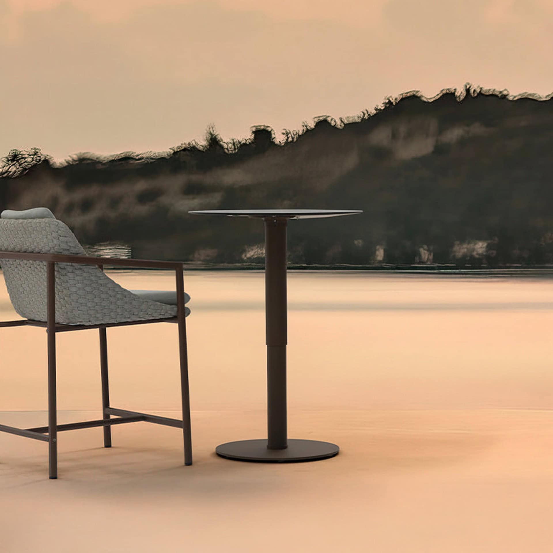 Seaside outdoor patio furniture with modern chairs and table overlooking the ocean.