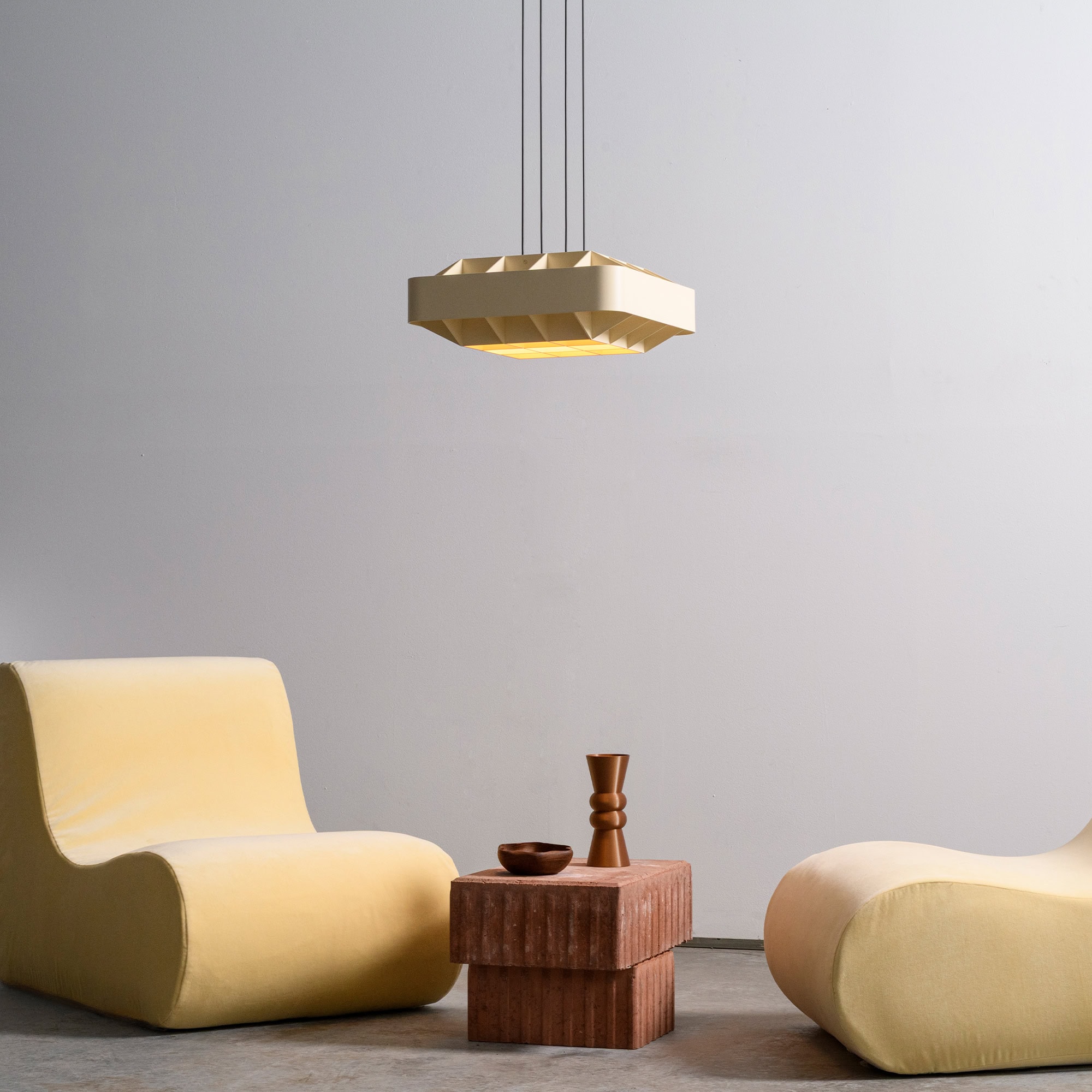 Modern minimalist living room furniture with soft yellow lounge chairs and a unique pendant light.