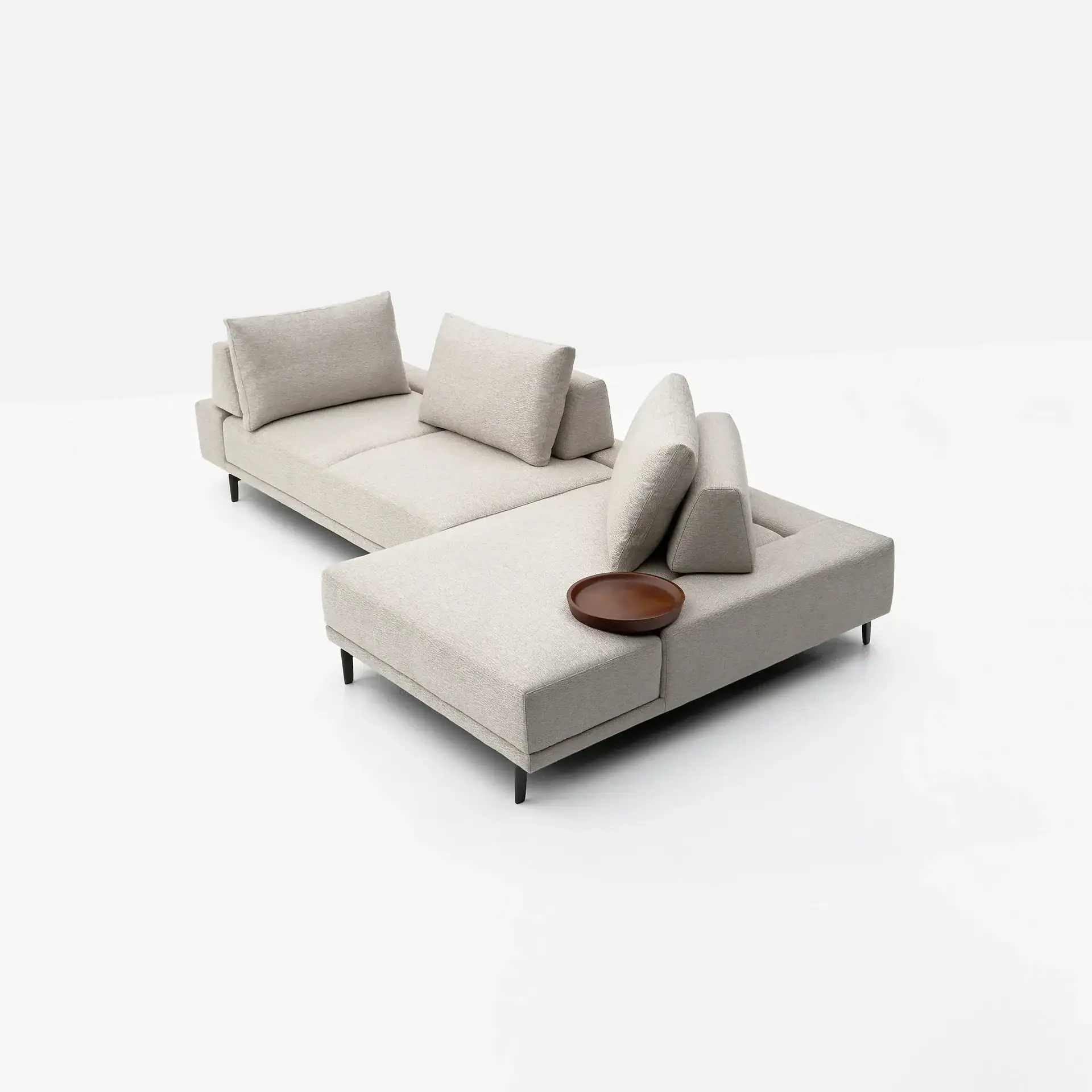 A light beige L-shaped sectional sofa with a wooden tray on its armrest, set against a white background.