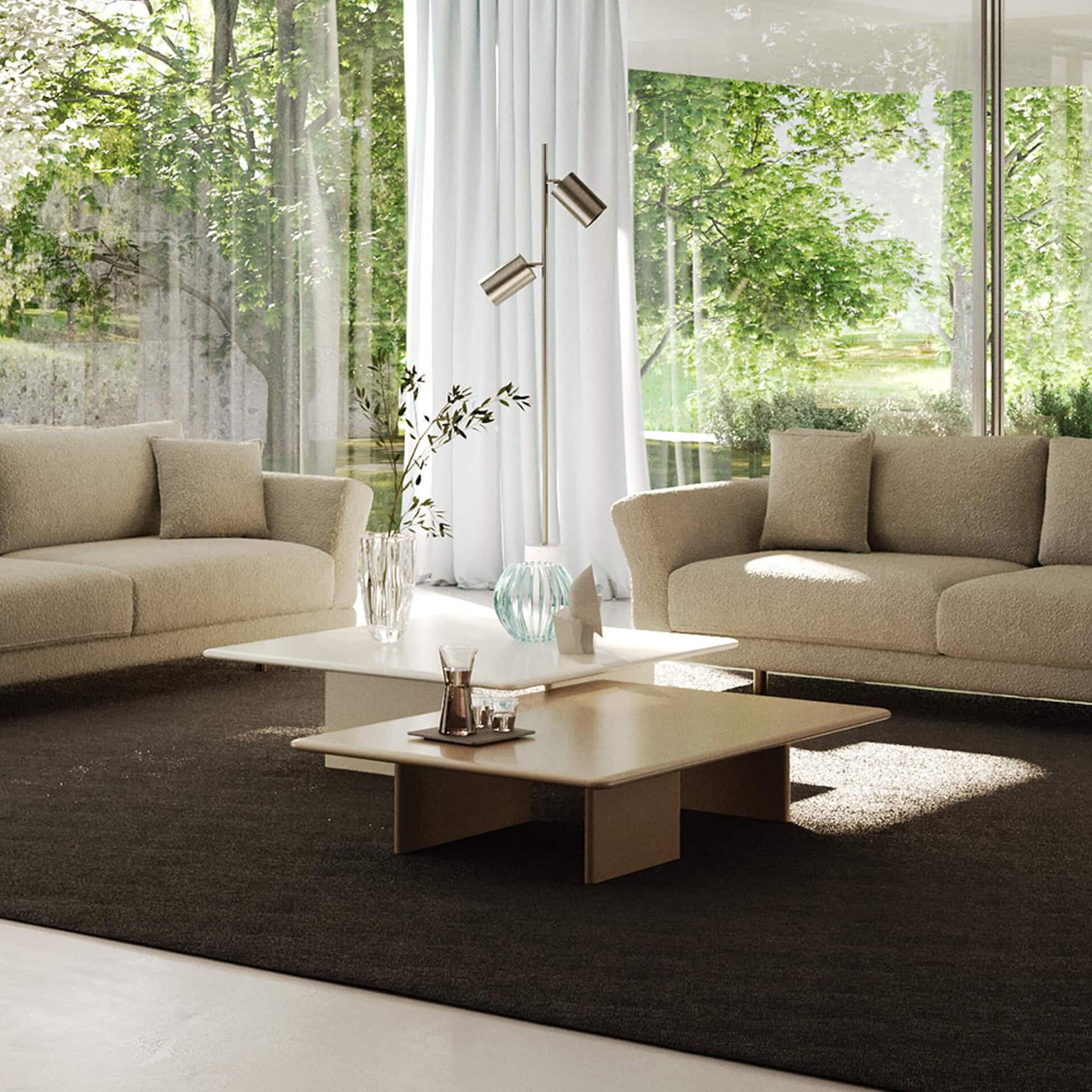 Contemporary beige sofas with coffee tables in a bright, modern living room featuring large windows and greenery.