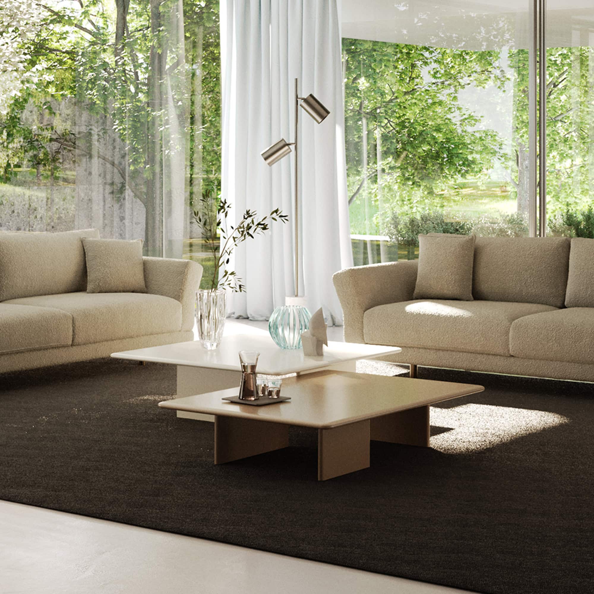 Contemporary beige sofas with coffee tables in a bright, modern living room featuring large windows and greenery.