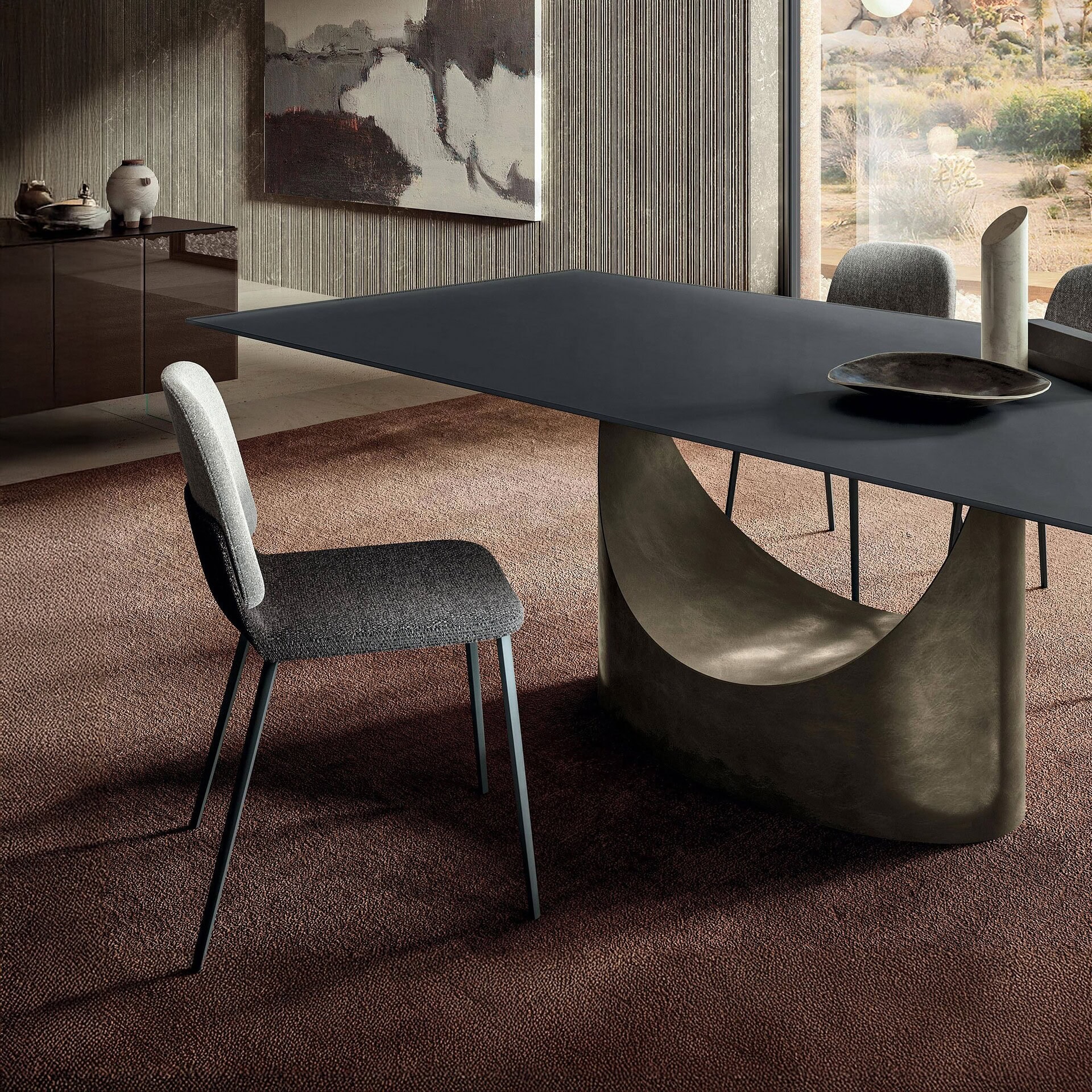 Contemporary dining table with sculptural base and modern upholstered chairs.