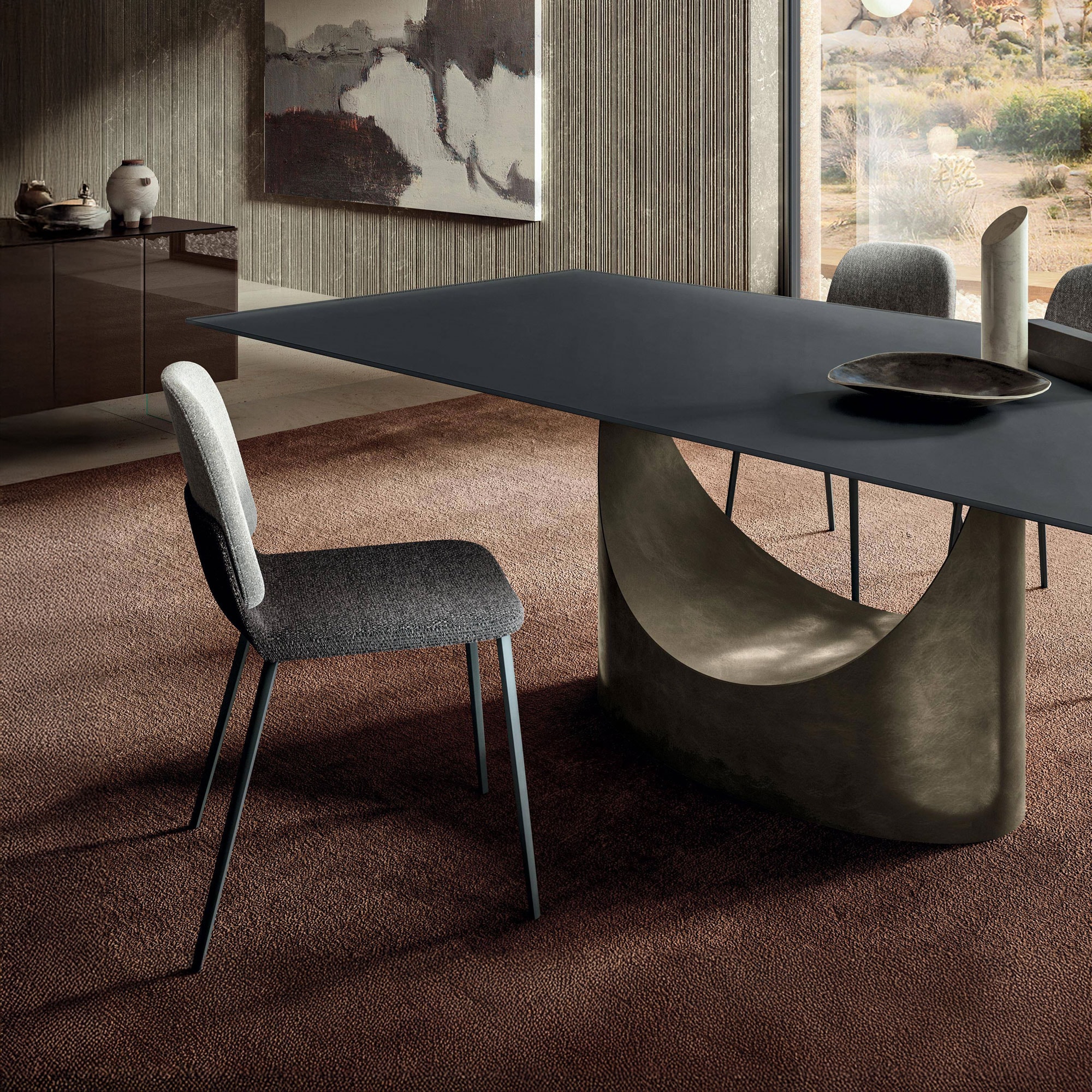 Contemporary dining table with sculptural base and modern upholstered chairs.