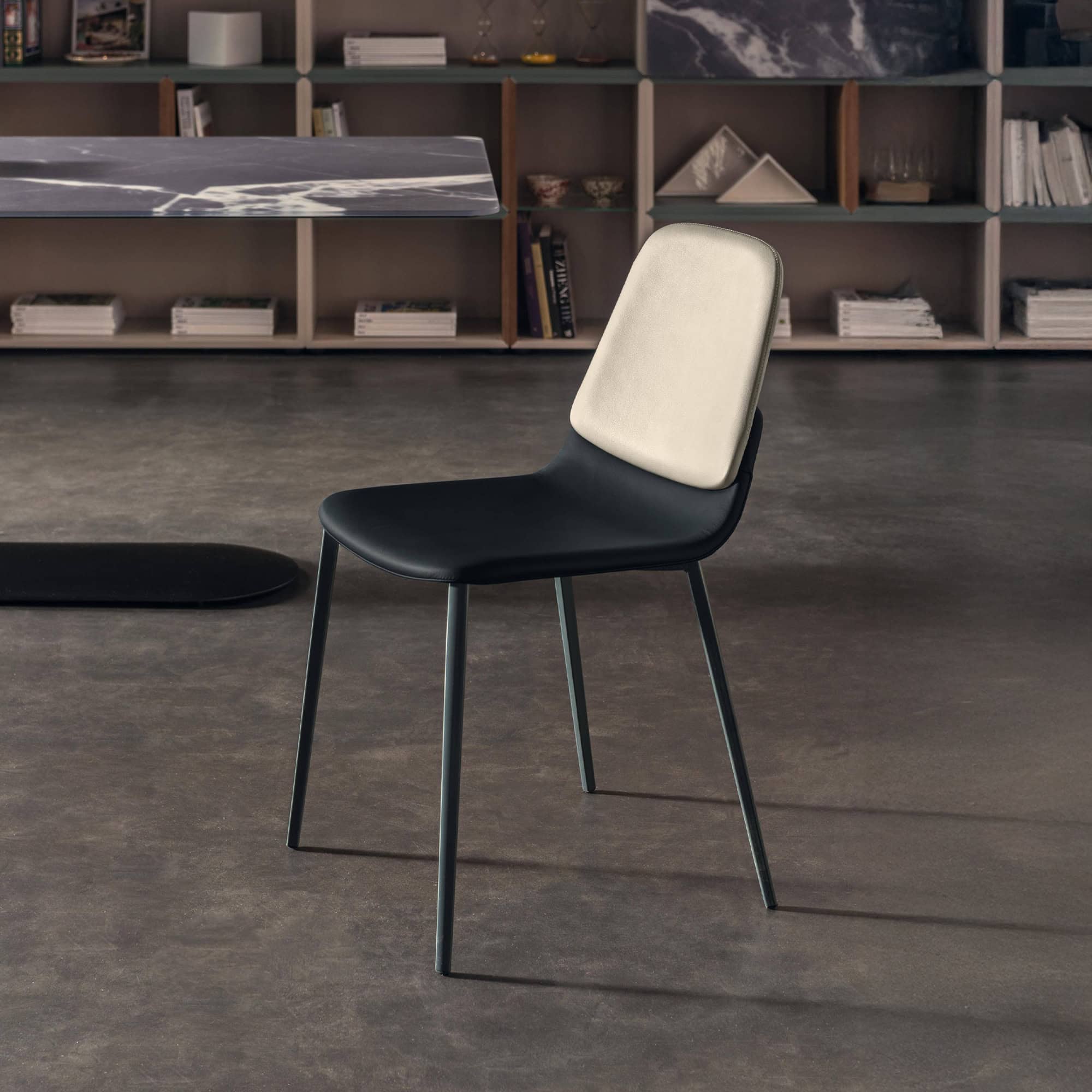 Modern dining chair with black leather seat and beige backrest, sleek design.