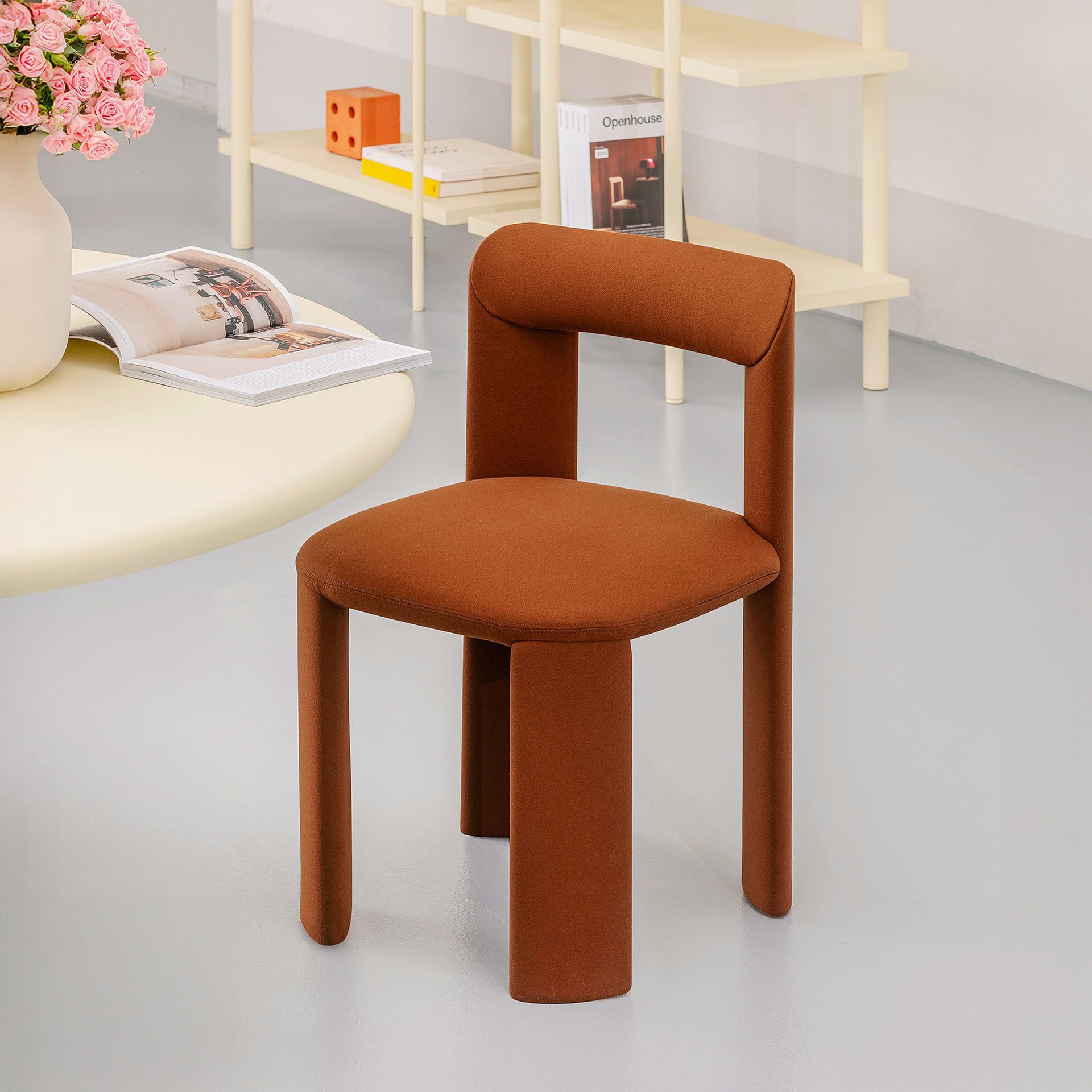 Modern rust-colored upholstered accent chair with rounded legs.