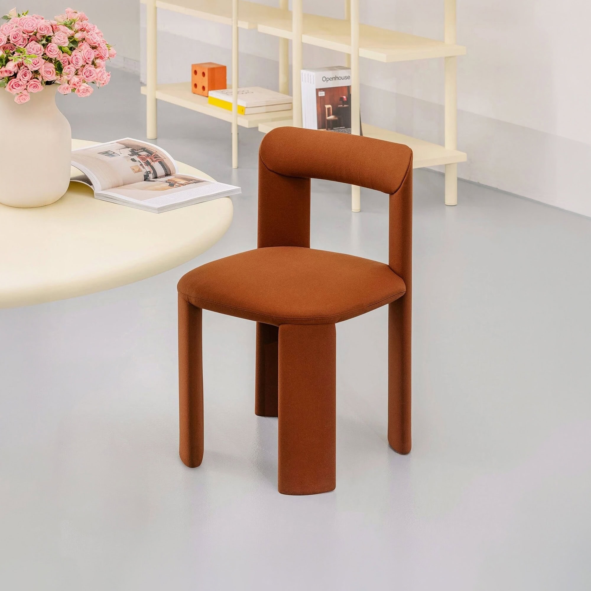 Modern rust-colored upholstered accent chair with rounded legs.