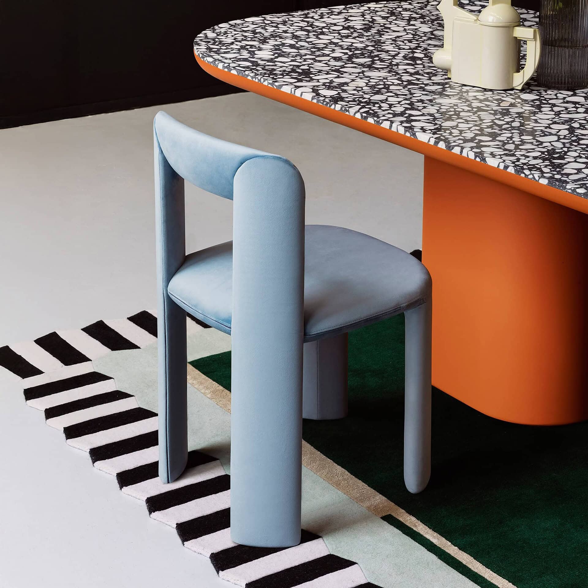 Feminine blue upholstered dining chair with curved backrest and cylindrical legs.