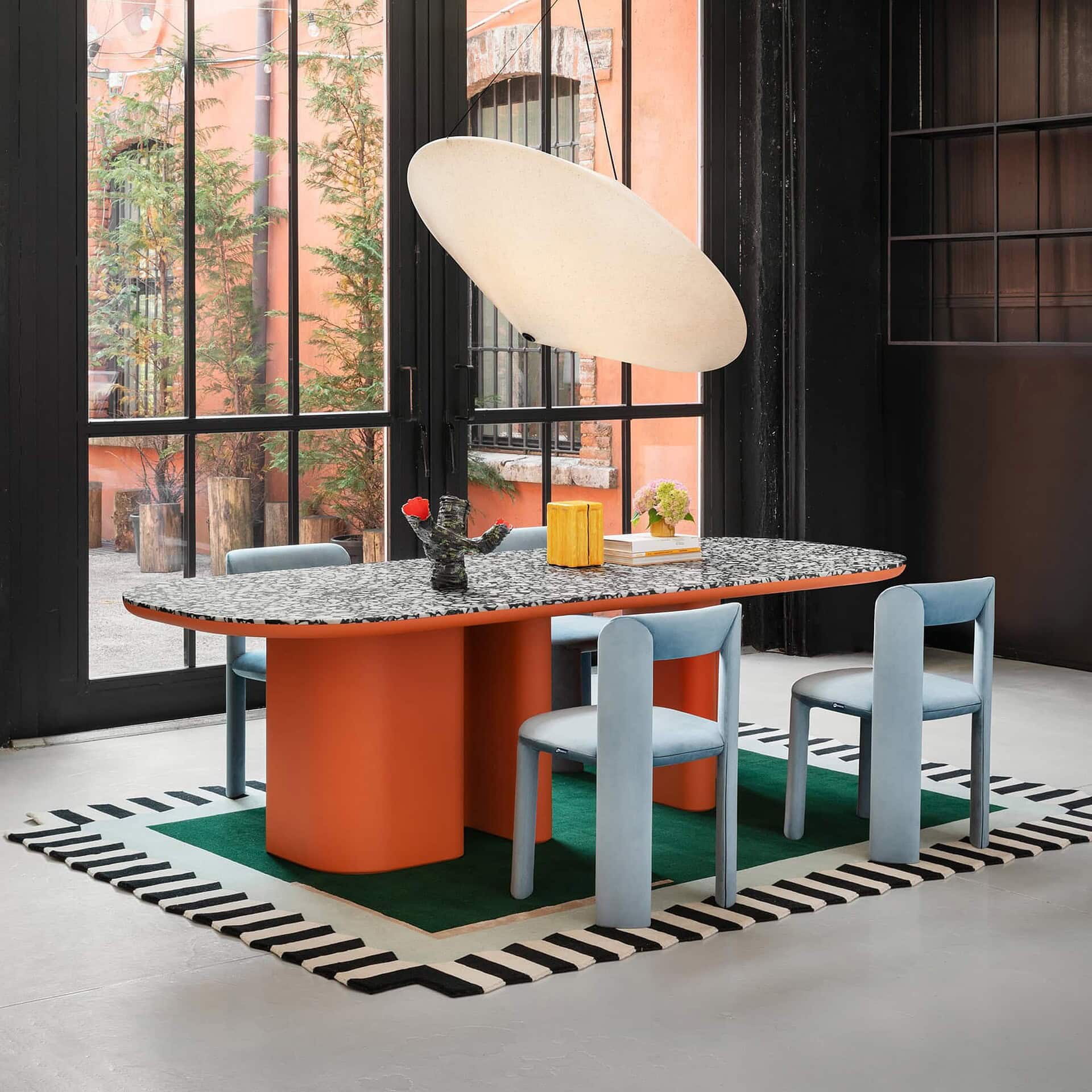 Elegantly designed modern dining table with colorful legs and unique patterned surface, set inside a stylish industrial-inspired space.