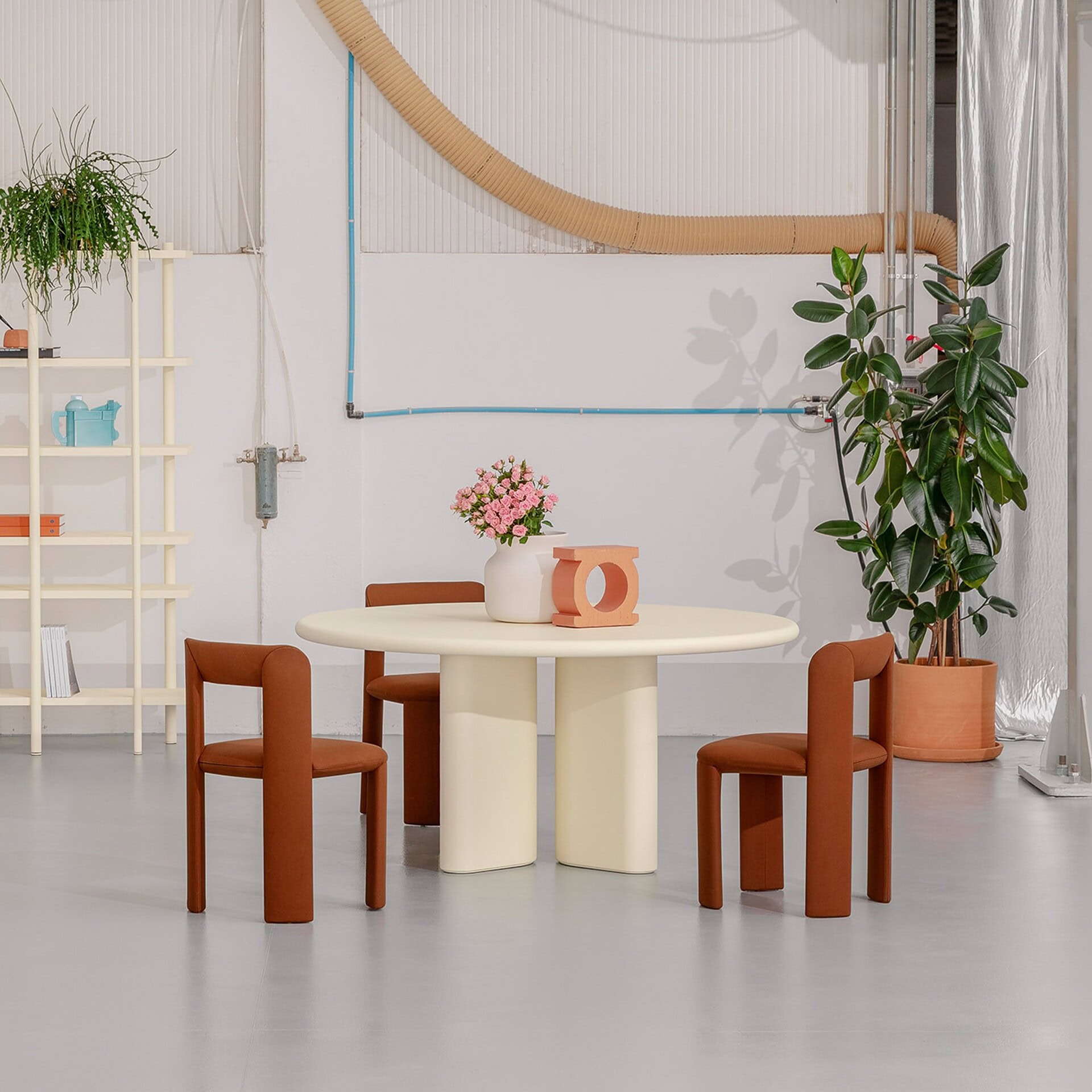 Concrete round dining table with brown upholstered chairs, modern minimalist design, natural lighting.