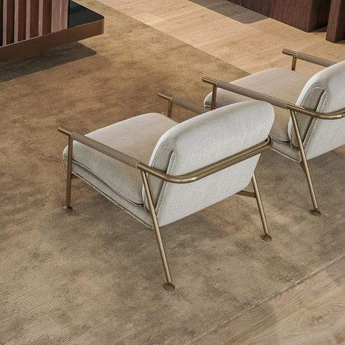 1. Modern beige lounge chair with metallic armrests and wood-paneled walls.