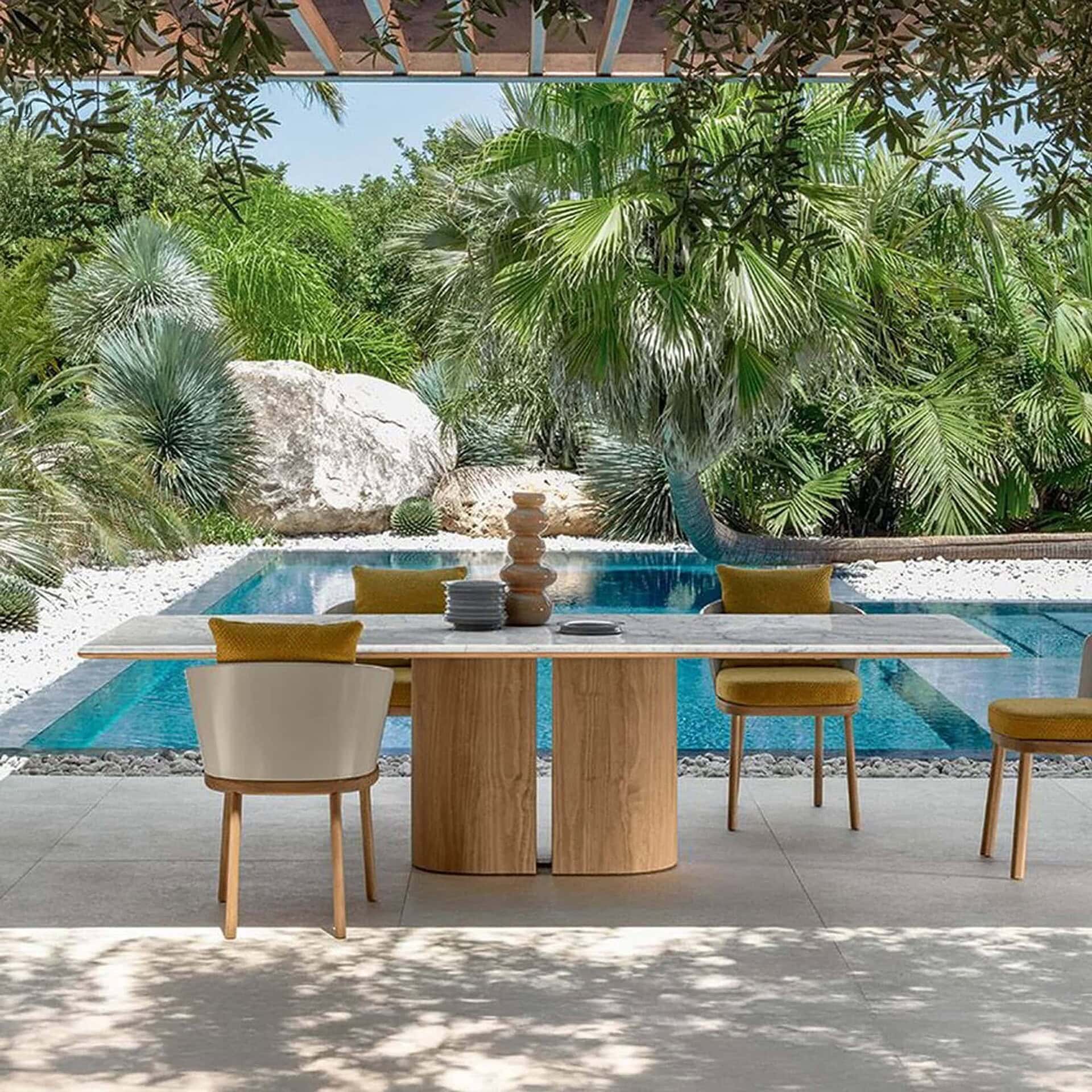 Contemporary outdoor dining table with natural wood finish and lush tropical landscaping.