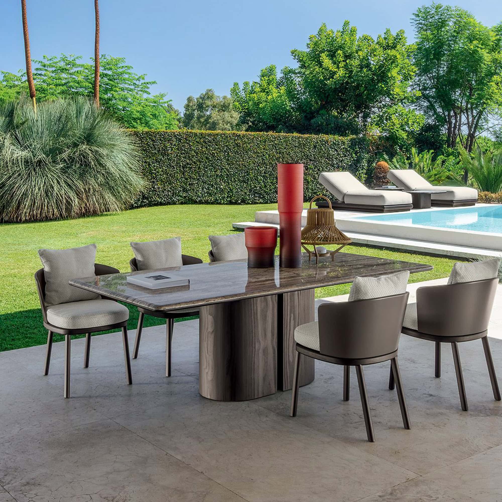 Elegant outdoor dining table with cushioned chairs in a lush backyard setting.