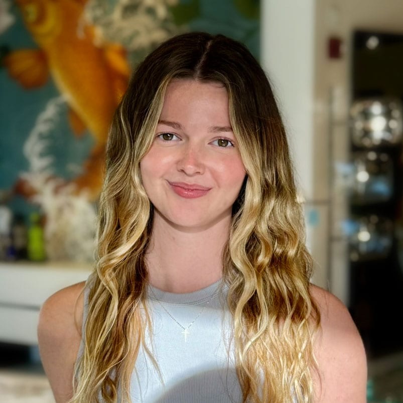 Warm woman portrait with long wavy hair and a gentle smile in a modern home environment.