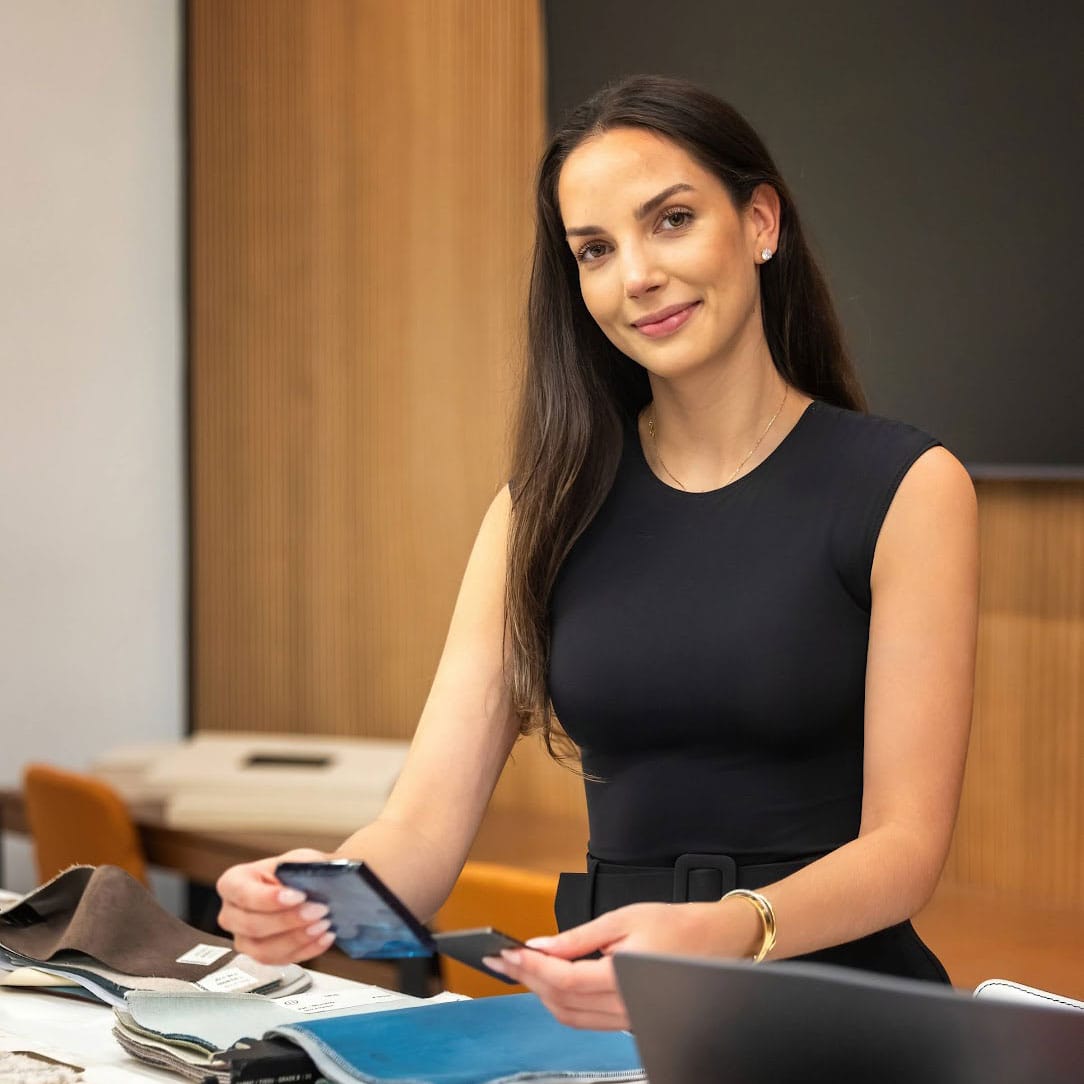 Elegant woman in black sleeveless dress showcasing modern interior design and furniture showroom at Sklar Furnishings.
