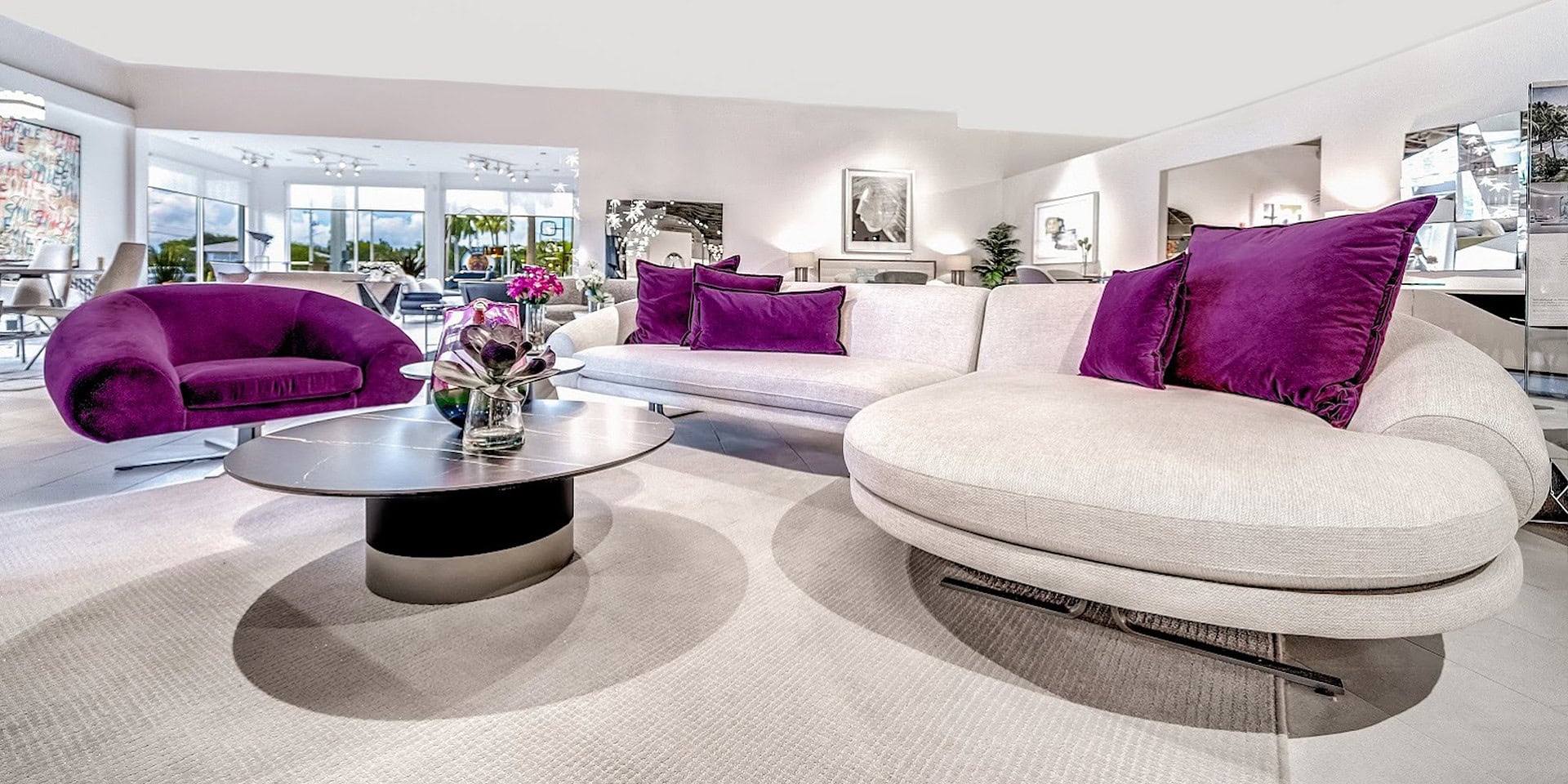 Soft contemporary sectional sofa with purple accent pillows in modern living room with glass windows and bright decor.