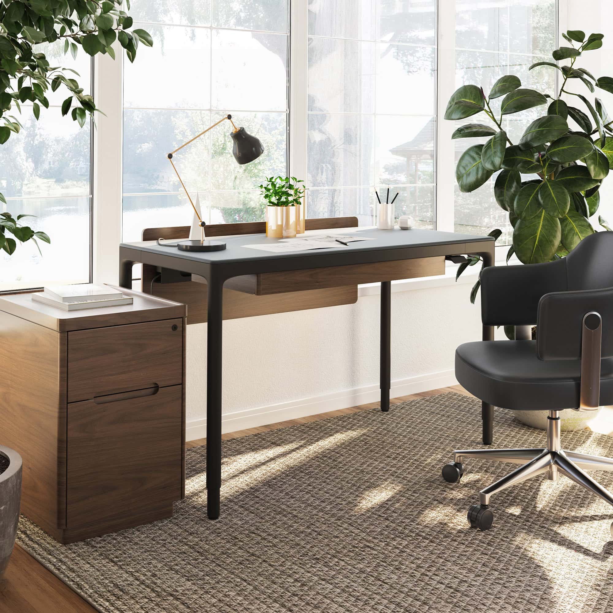 Stylish office workspace featuring a modern desk with black and wood accents, surrounded by greenery.