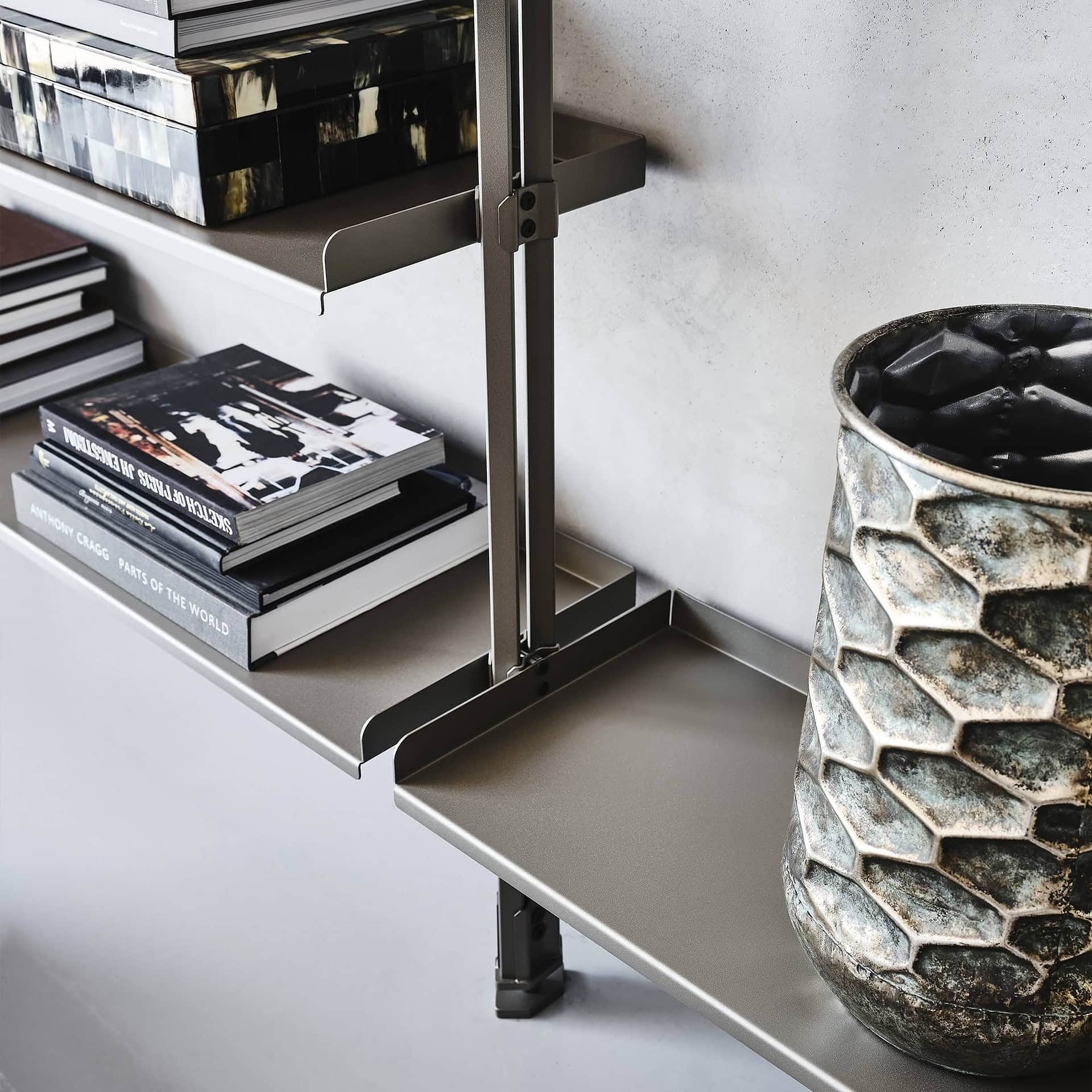 Sleek modern shelving with books and decorative vase on metallic surface, minimalist home decor.