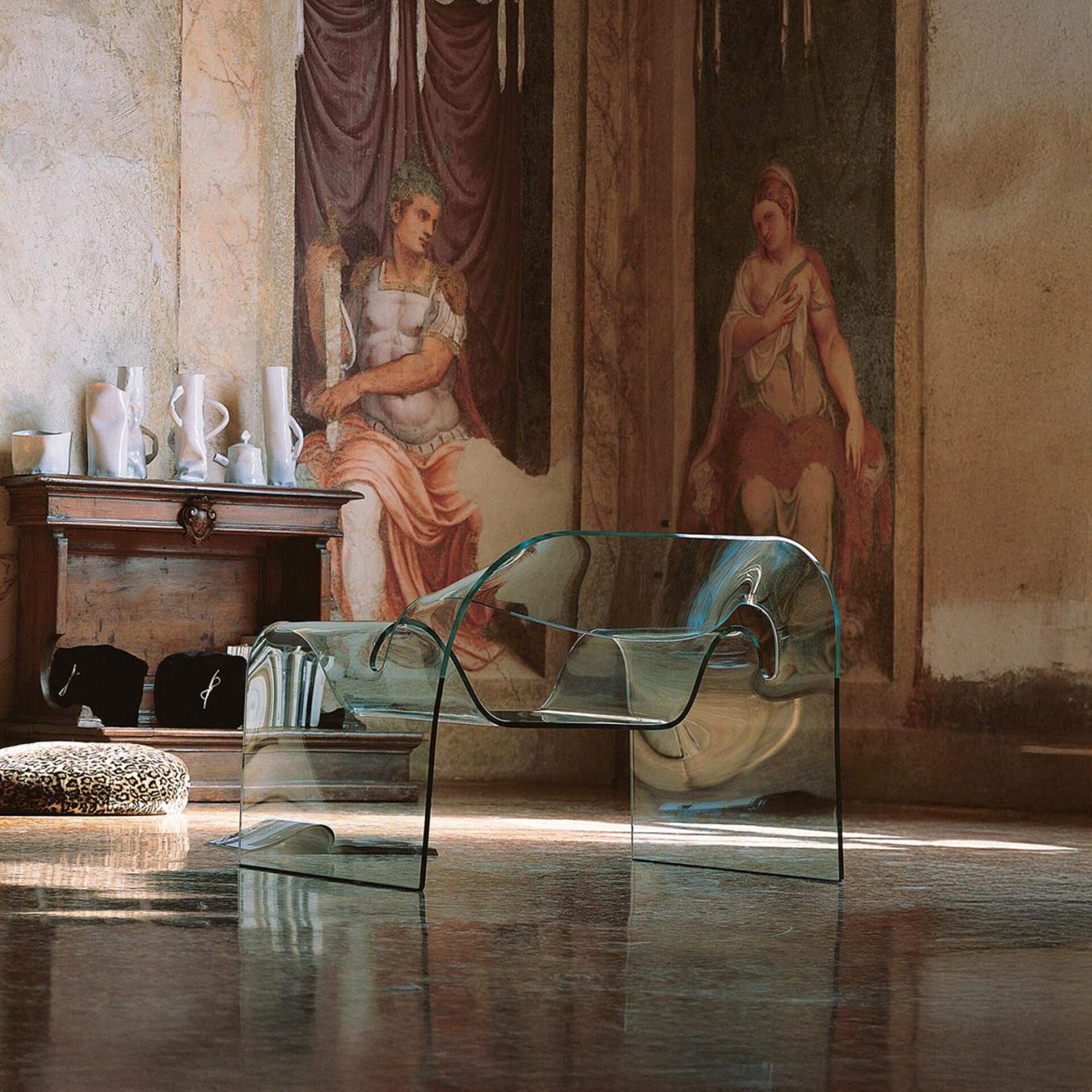 Sleek transparent acrylic chair in a luxurious, historic art-filled interior with mural walls.