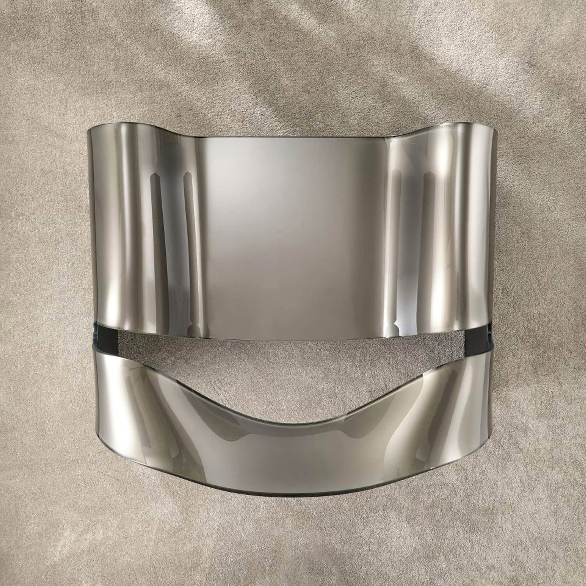 Sleek stainless steel decorative wall shelf with curved design for modern interior decor.