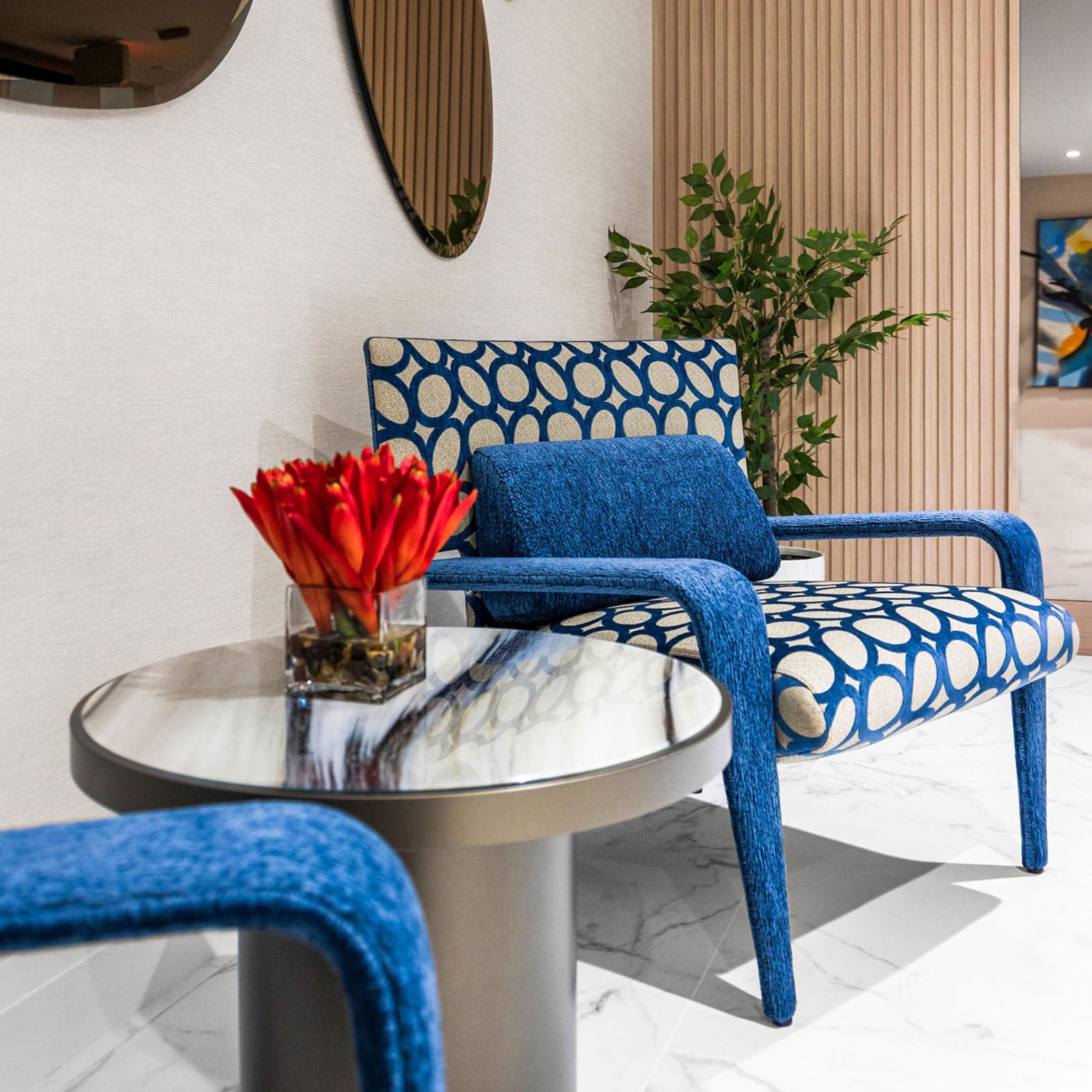 Elegant blue patterned lounge chair with a matching bolster pillow, modern interior design by Sklar Furnishings.
